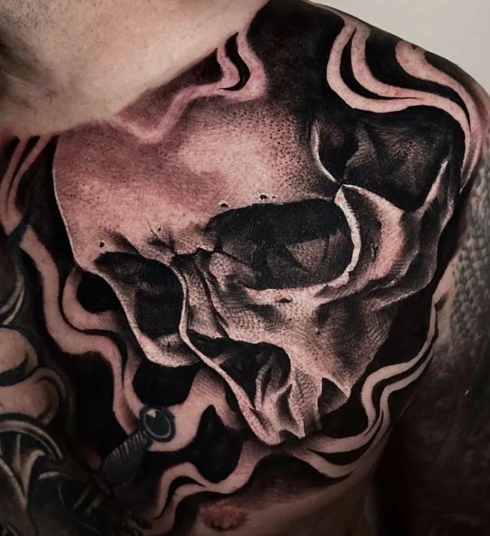Black and grey skull tattoo spanning the chest and shoulder with flowing abstract shading, completed by Cody Eckenrode at CREate Tattoo Studio.
