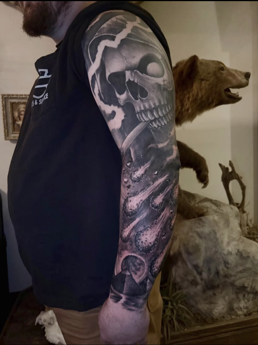 Black and grey arm sleeve tattoo featuring a skull with cosmic elements, asteroids, and a pyramid, completed by Cody Eckenrode at CREate Tattoo Studio.