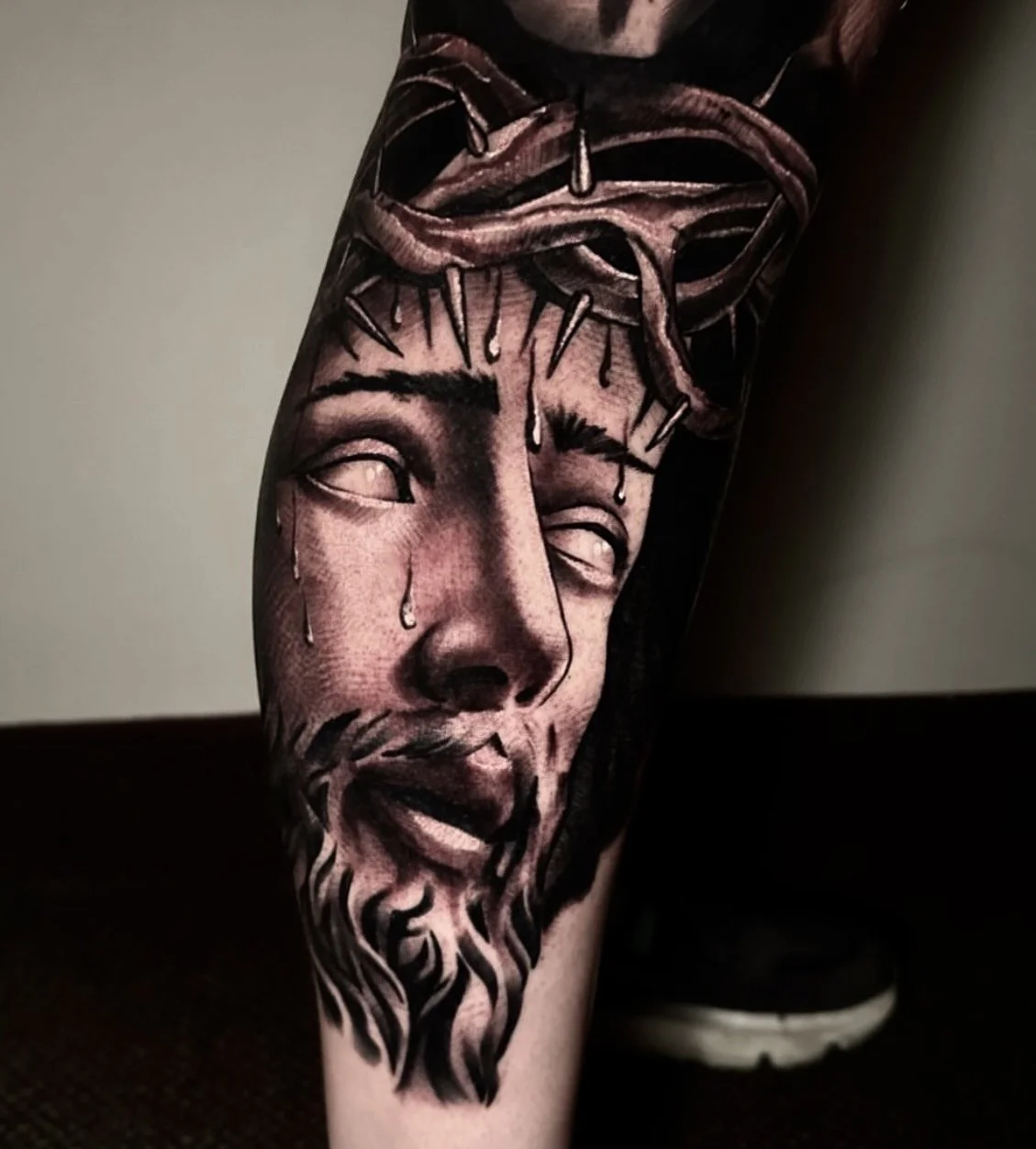 Black and grey portrait tattoo of Jesus with a crown of thorns and tears, completed by Cody Eckenrode at CREate Tattoo Studio.