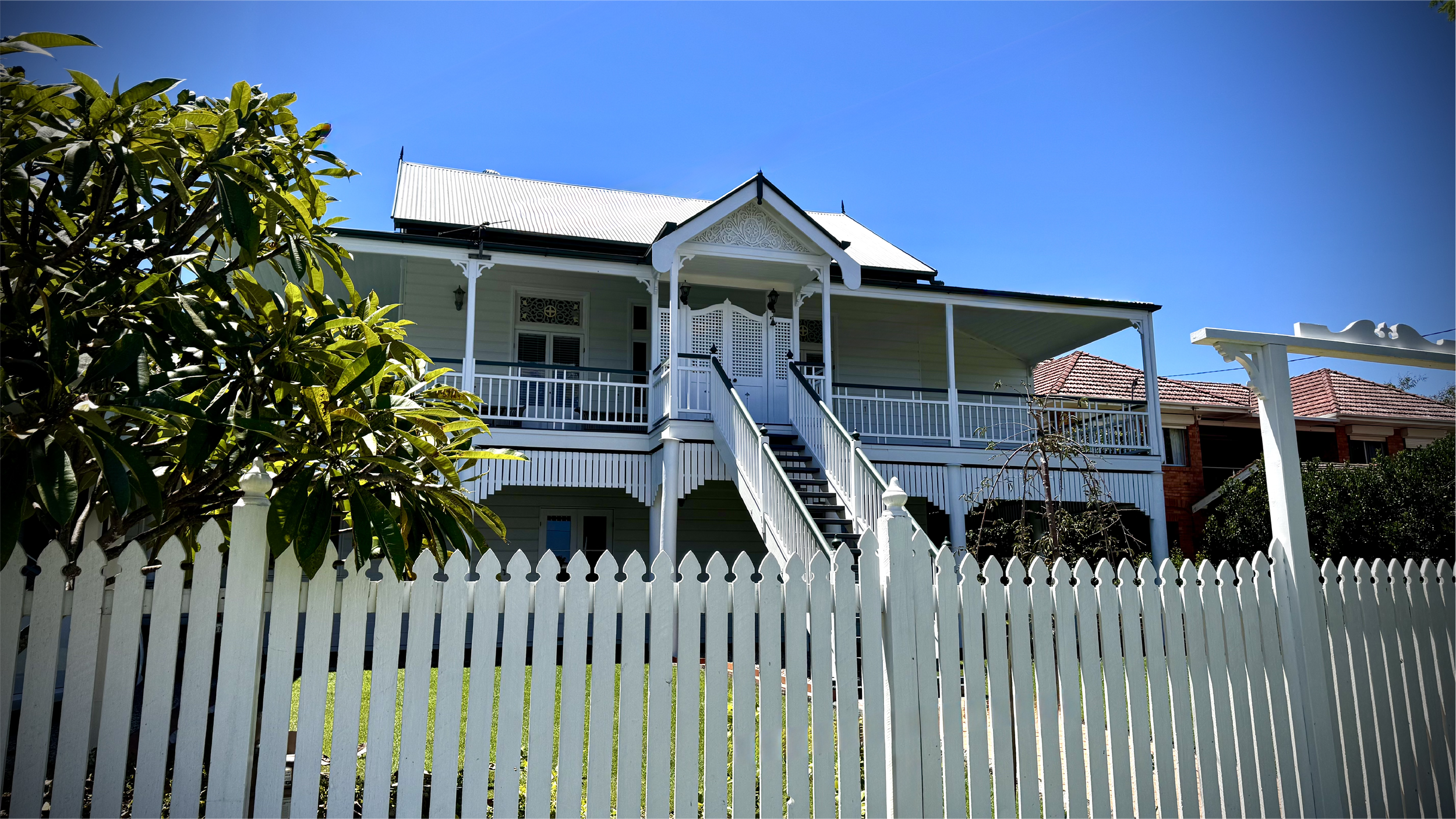 Colonial-style house with a white picket fence and veranda.
