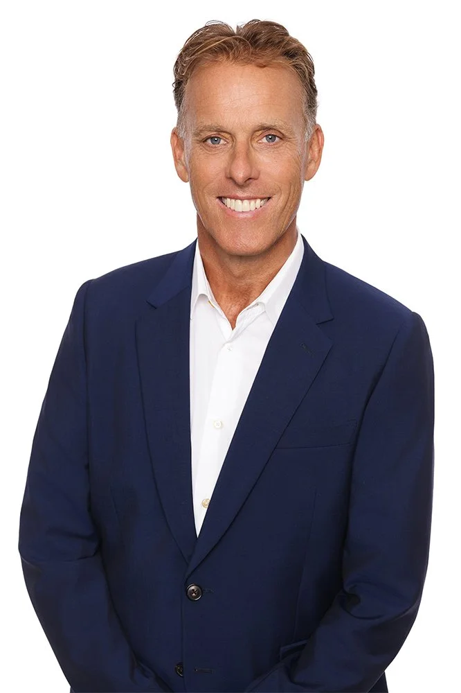 Adam Kingston, Director and Principal Mortgage Broker of Best Foot Forwards Mortgage Solutions, is Smiling, wearing a blue suit and white shirt on a white background.