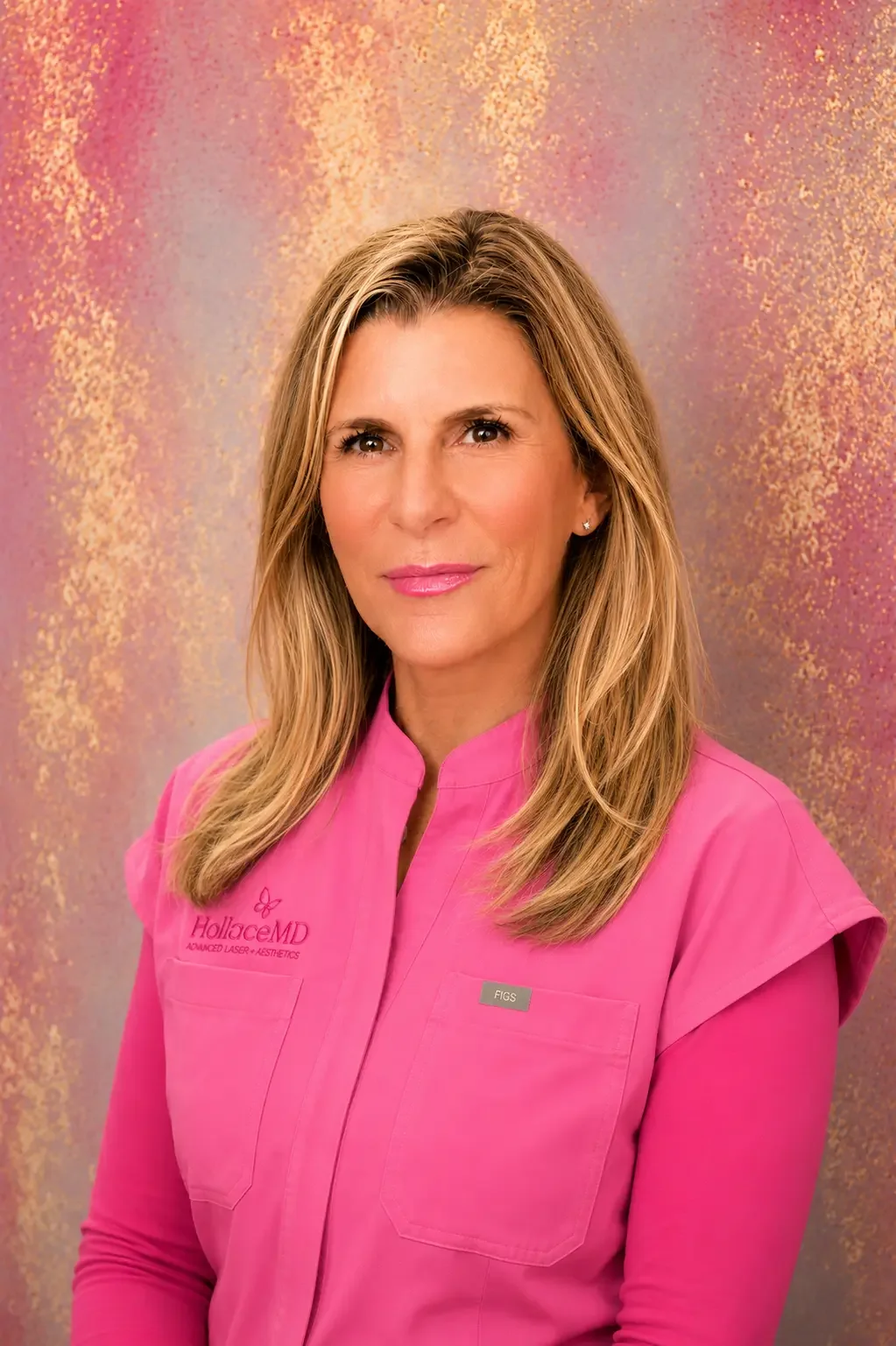 A woman with blonde hair in a pink garment with a logo reading "HolliceMD" and a name tag reading "FIGS" poses against a colorful, textured backdrop.