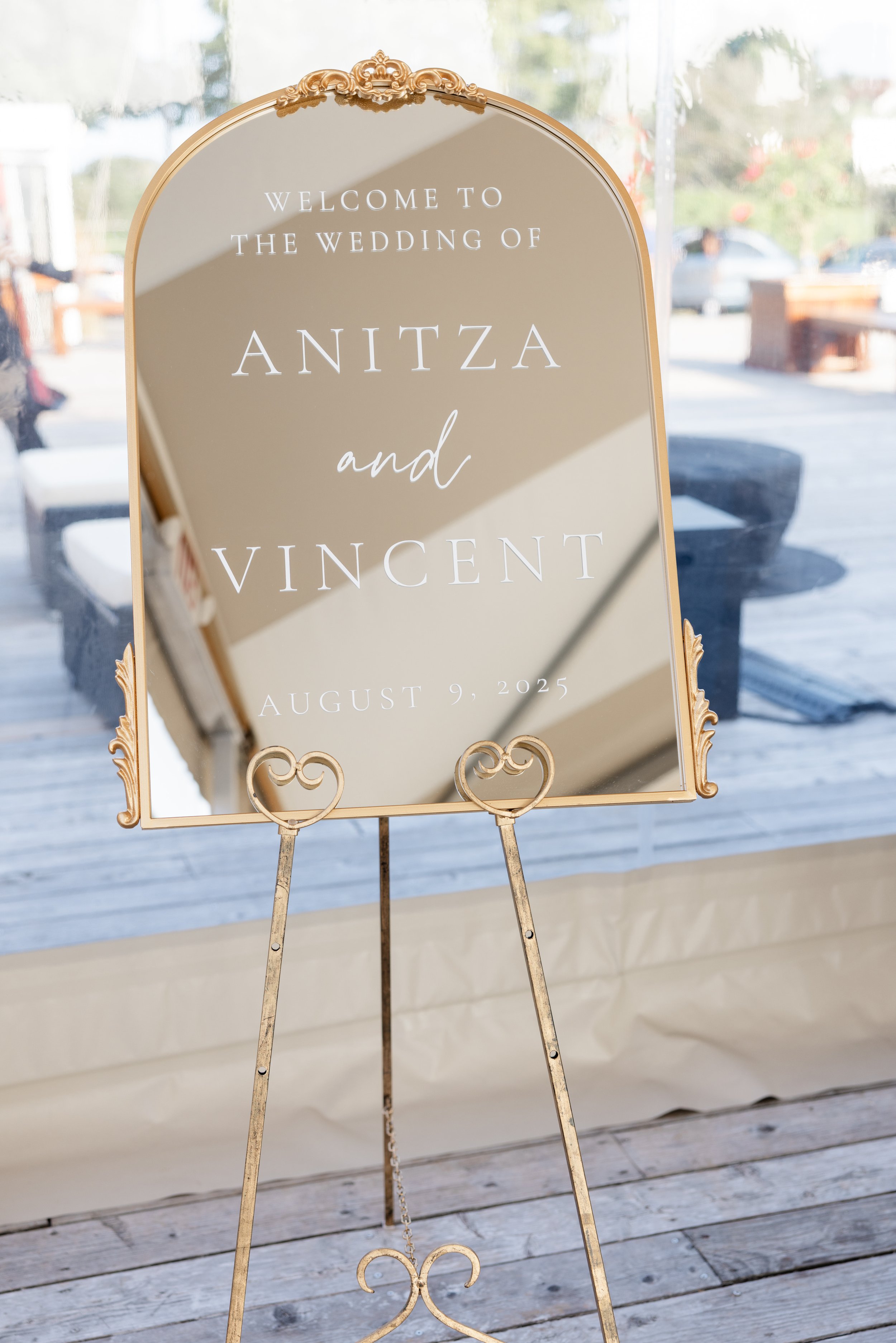 Ornate gold mirror wedding welcome sign featuring white vinyl lettering at a Newport wedding reception - OceanCliff Hotel