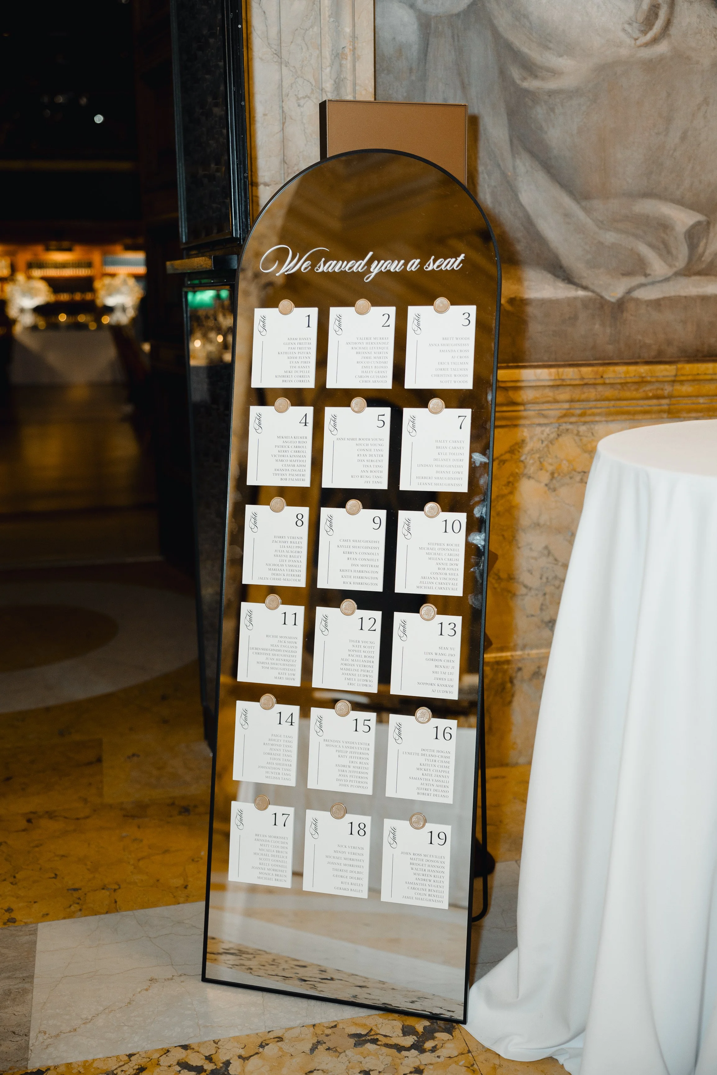 Modern black mirror wedding seating chart featuring white vinyl-lettered script and card stock and wax seal - Boston Public Library