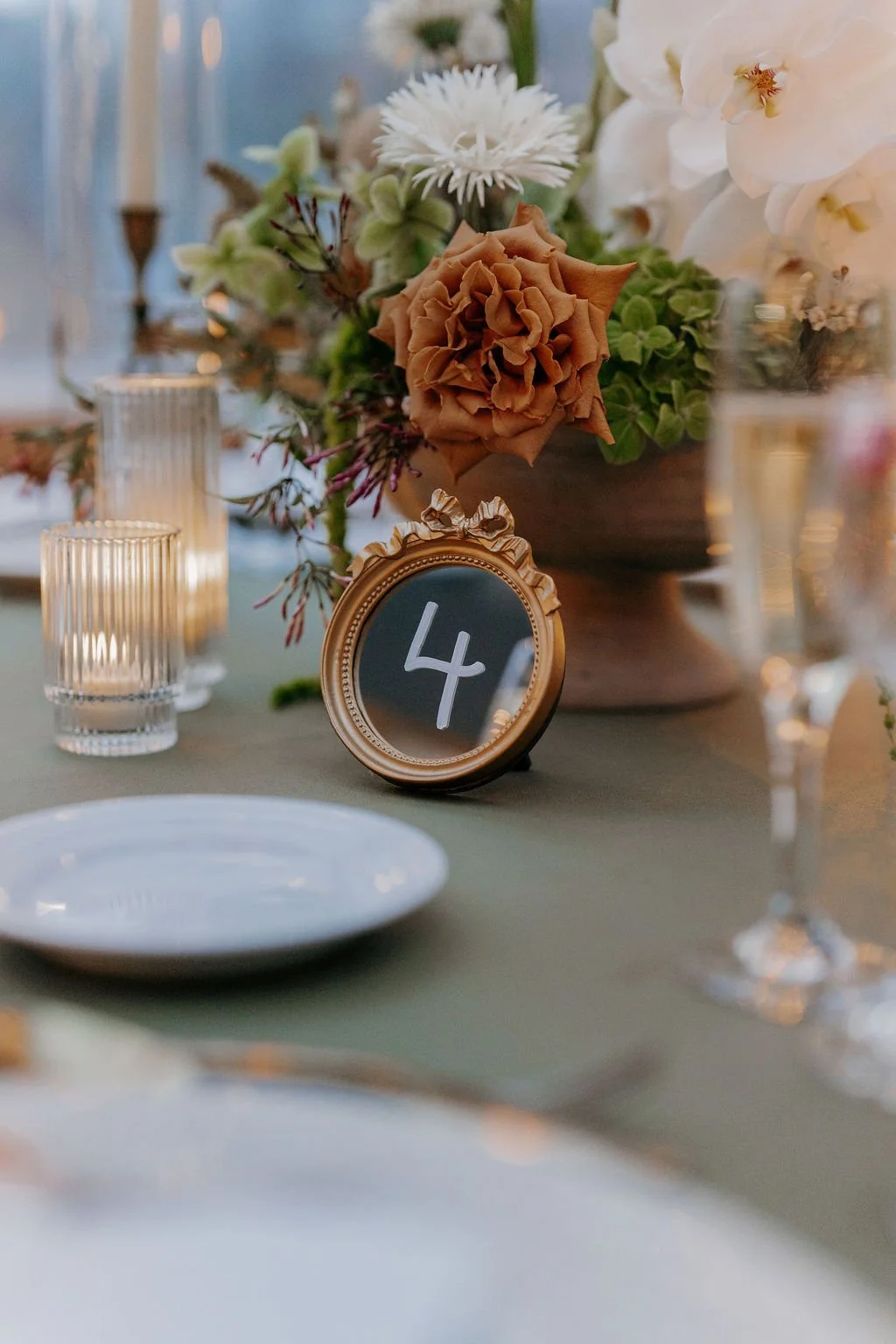 Vintage ornate gold mirror wedding table number sign featuring white hand-lettered calligraphy - Bostonian Hotel
