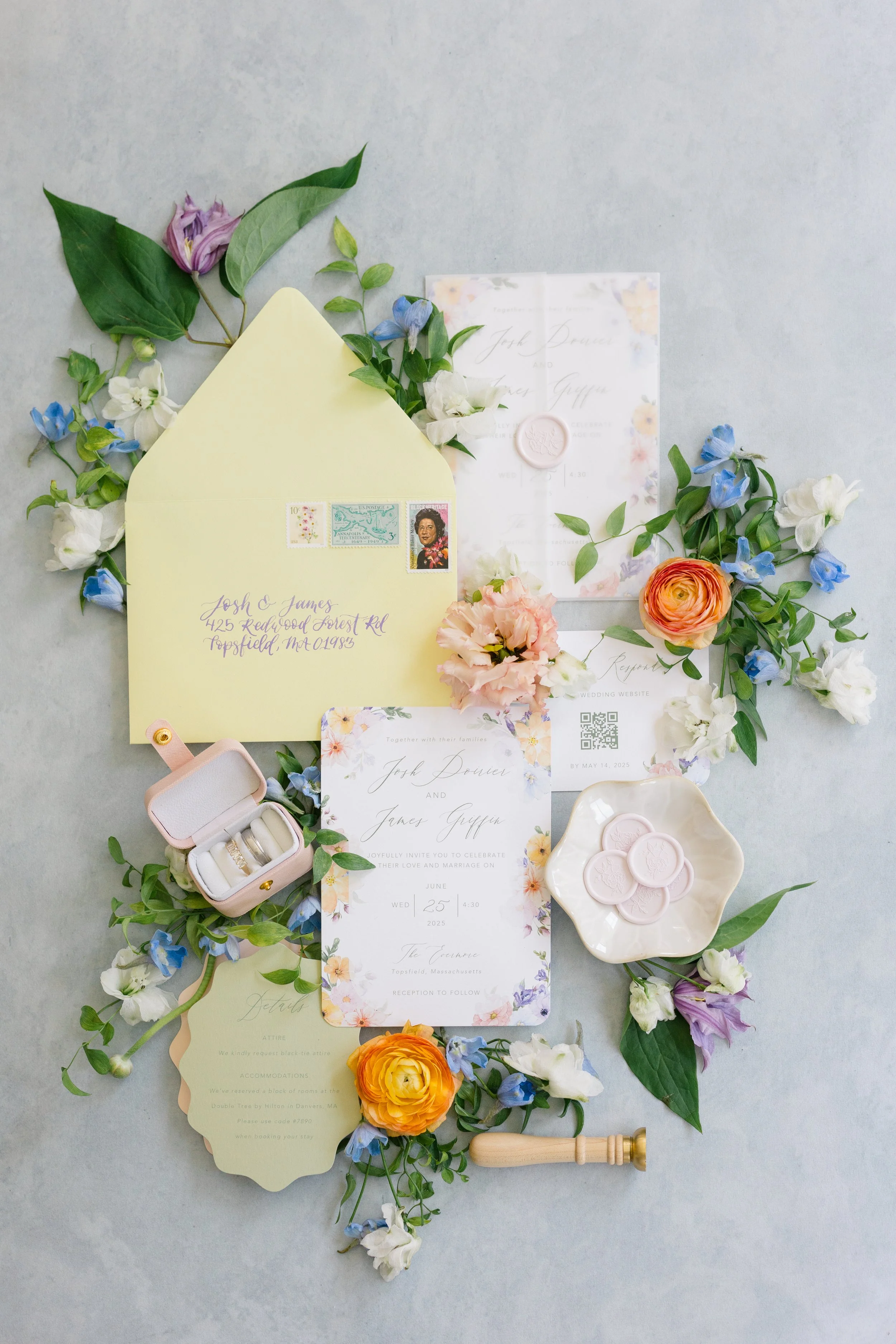 Garden floral invitation suite, wedding rings in a pink ring box, custom peony wax seals on a dish, and colorful flowers including ranunculus and sweet peas on a light background.