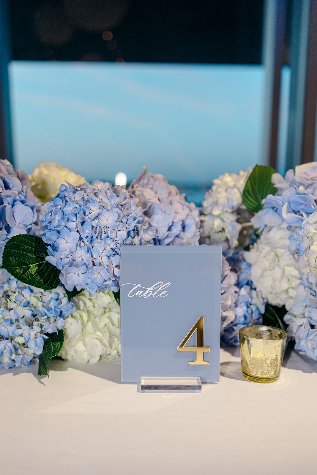 Modern coastal blue acrylic wedding table numbers with custom white vinyl lettering, a gold mirror table number, and floral accents, for a classic, elegant coastal wedding at the ICA in Boston, MA