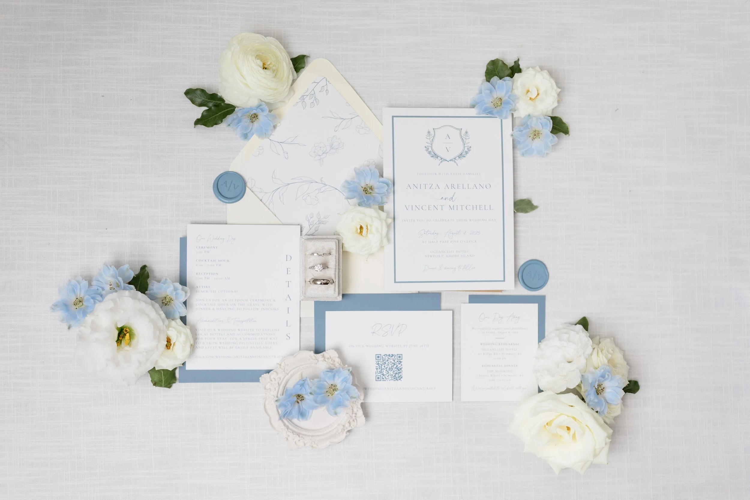 Custom, dusty blue coastal elegance bespoke wedding invitation suite with a floral envelope liner in a cream envelope, a custom wax seal, and lots of florals for a OceanCliff Hotel wedding in Newport, RI