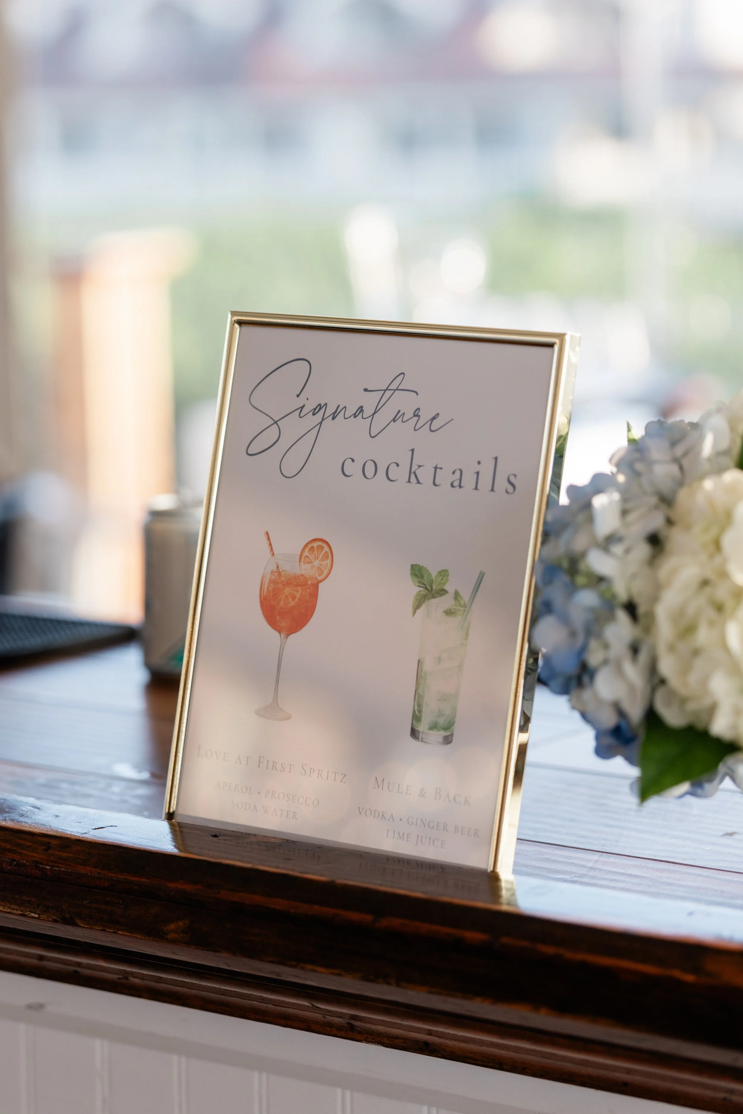 Gold frame wedding signature cocktail sign featuring watercolor artwork at a Newport wedding reception - OceanCliff Hotel