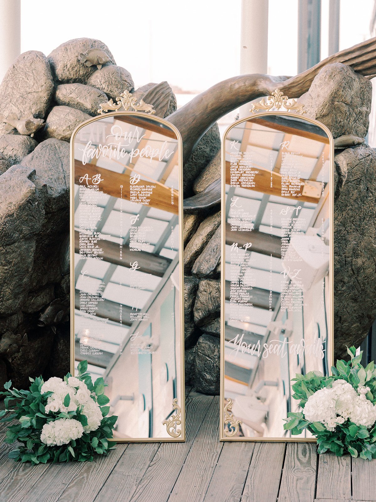Ornate gold mirror wedding seating chart featuring white hand-lettered calligraphy at a Boston wedding reception - New England Aquarium
