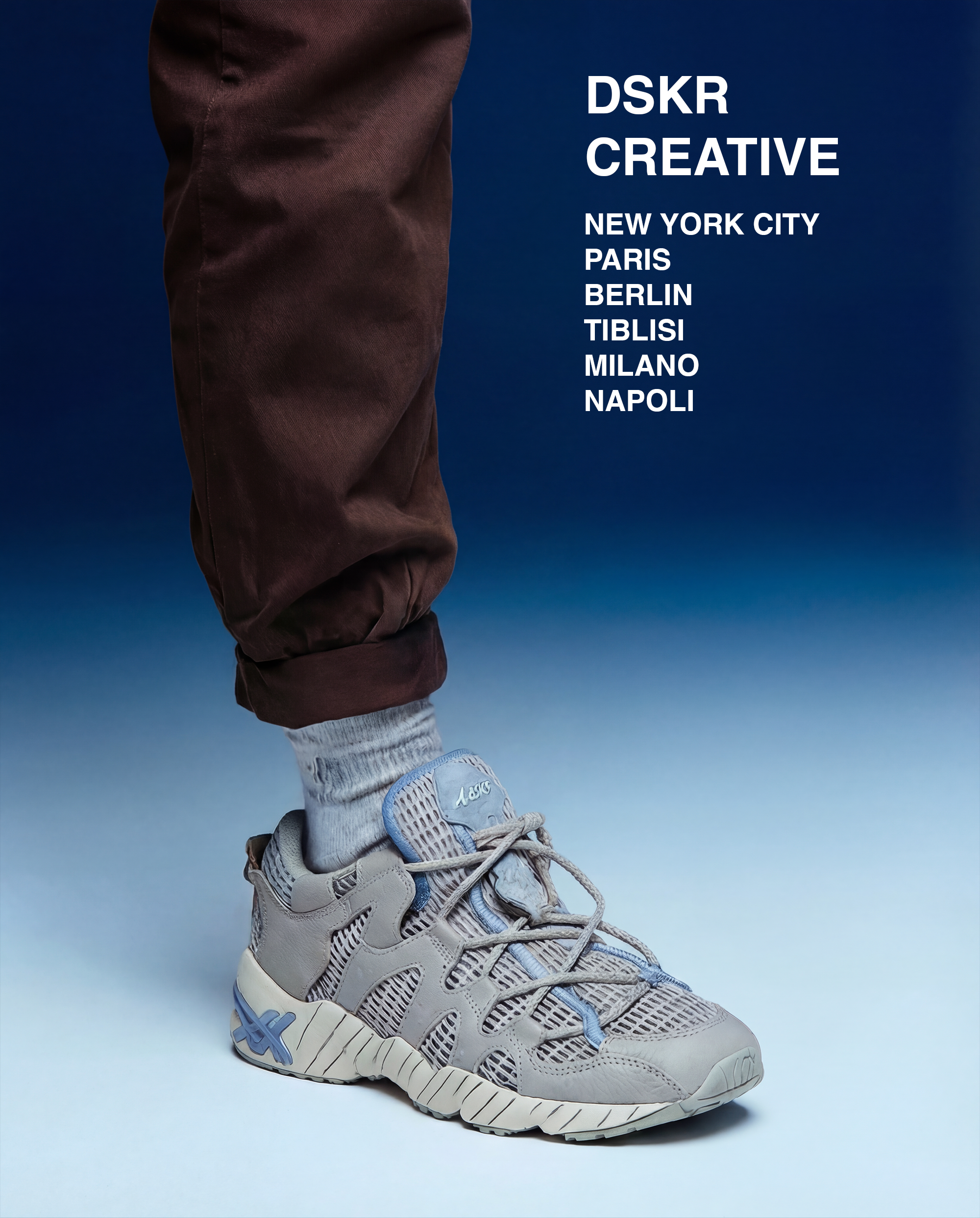 Close-up of a person's lower leg wearing brown pants, gray sneaker, and gray sock against a blue background with white text listing city names.
