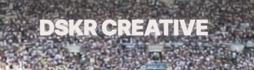 An aerial view of a large crowd of people gathered at an outdoor event, with the text "DSKR CREATIVE" displayed prominently in bold white letters in the center.