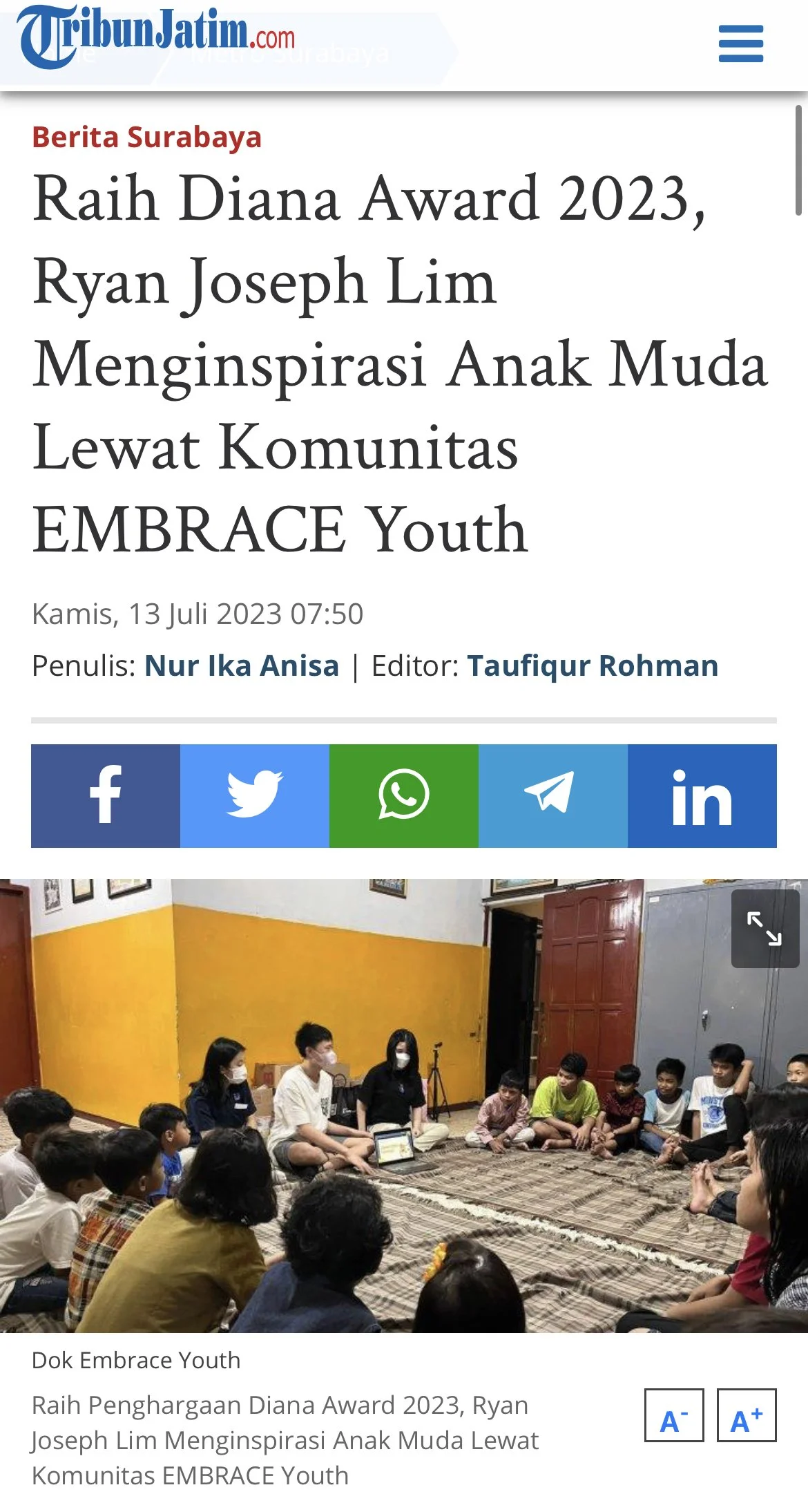 Children and young people sitting in a circle on the floor of a room with yellow and white walls, wearing face masks, during a community event.