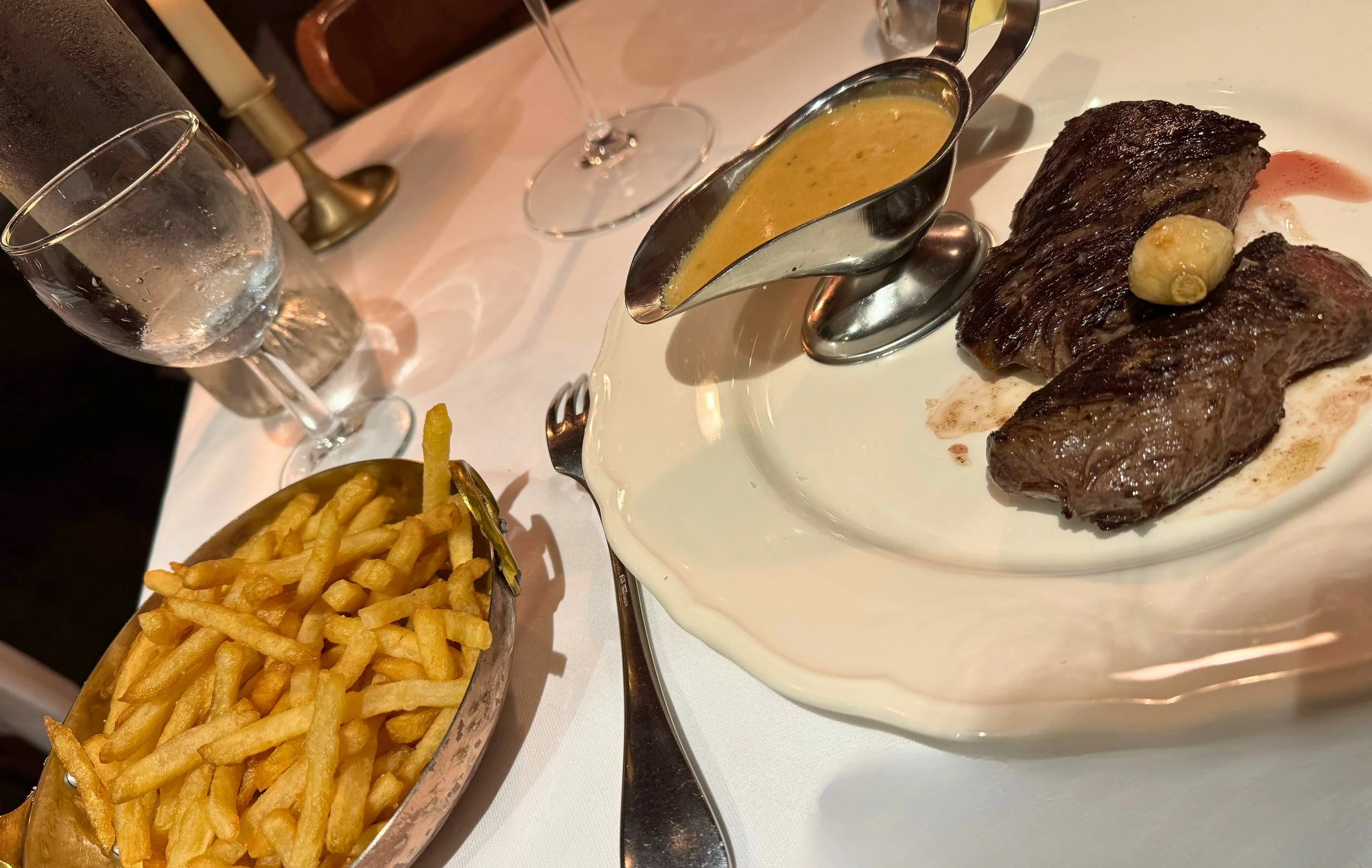french fries with steak and bleu cheese sauce on white tablecloth