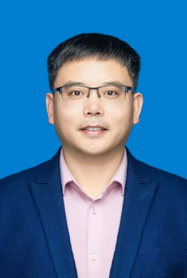 Headshot of a man wearing glasses, a pink collared shirt, and a dark blazer, against a blue background.