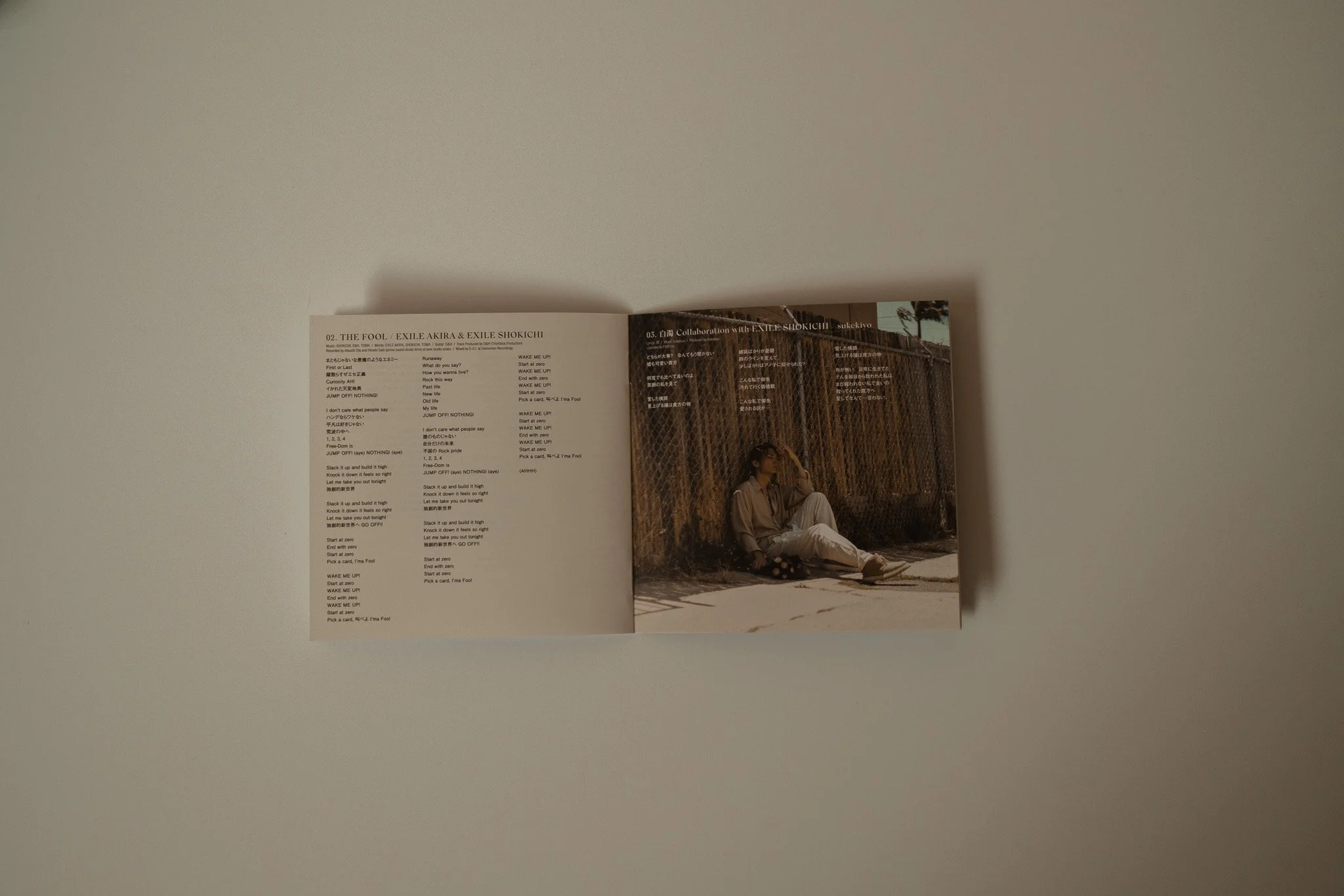 An open magazine lying on a light-colored surface, displaying a page with text on the left and a photo of a woman sitting against a fence on the right.