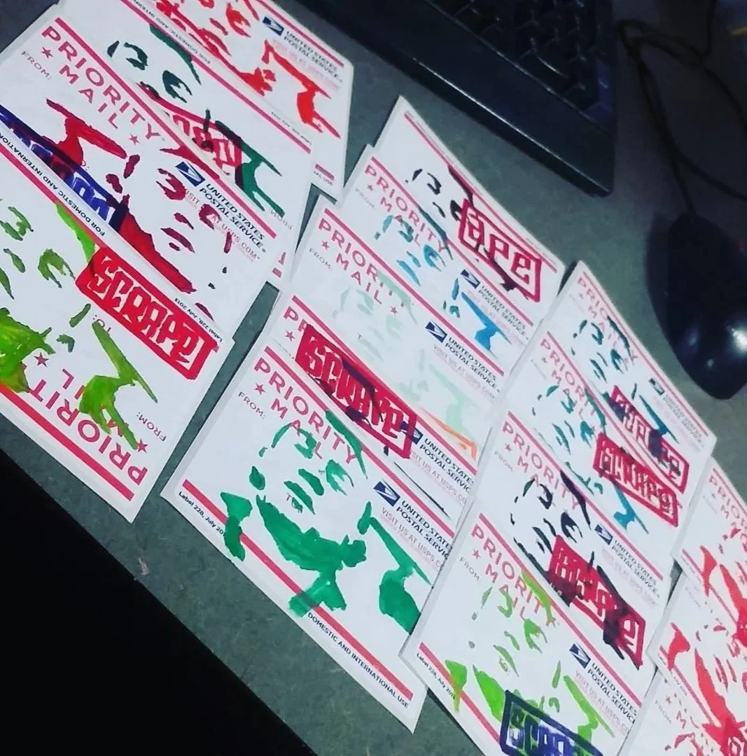 A table with multiple United States Postal Service Priority Mail shipping labels in various colors, some with red, green, and blue text and markings, overlapping each other.