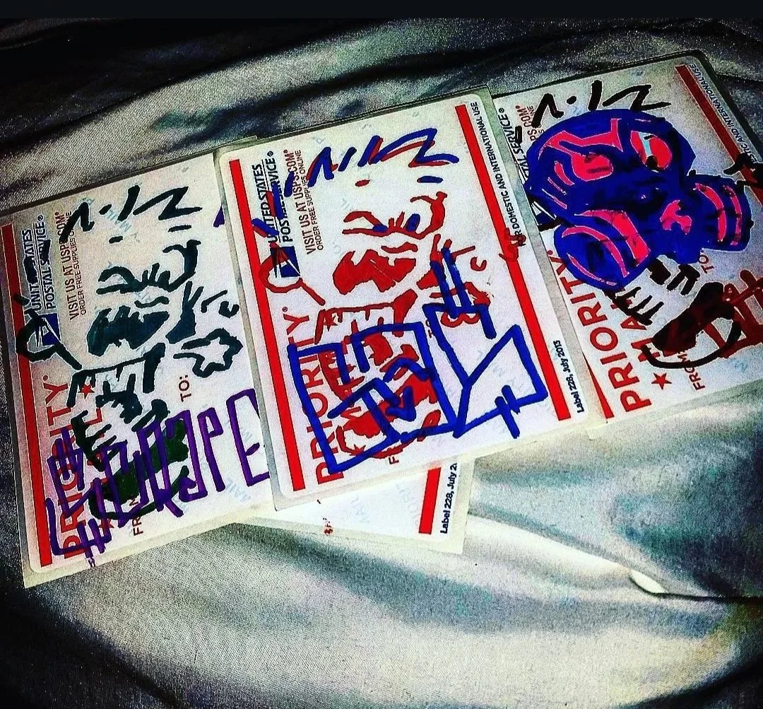 Three priority mail labels with handwritten messages and doodles in red, blue, purple, and black ink, attached to a metallic surface.