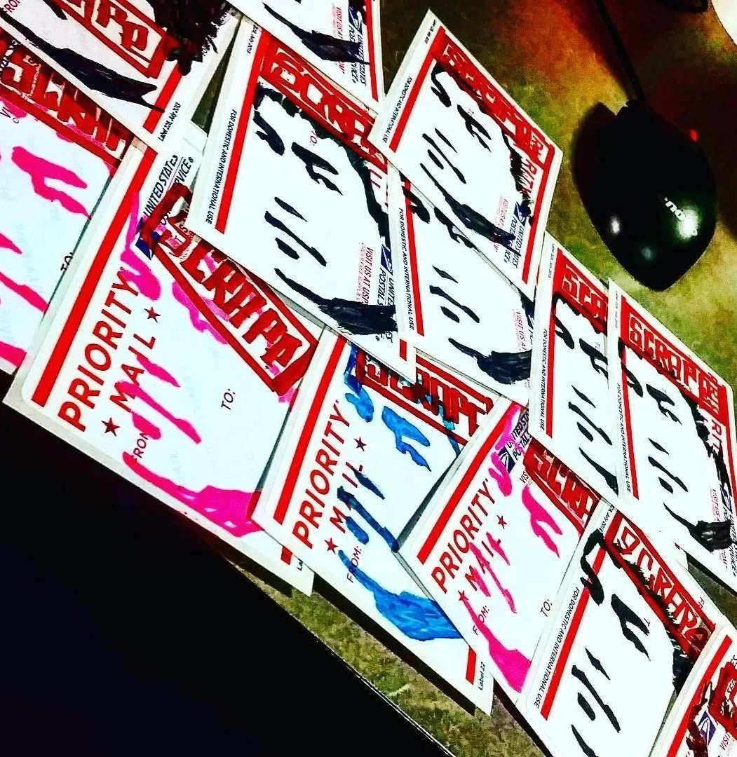 Several priority mailing labels with red crosses and handwritten black ink addresses, some with pink and blue markers, and a black computer mouse on a wooden surface.
