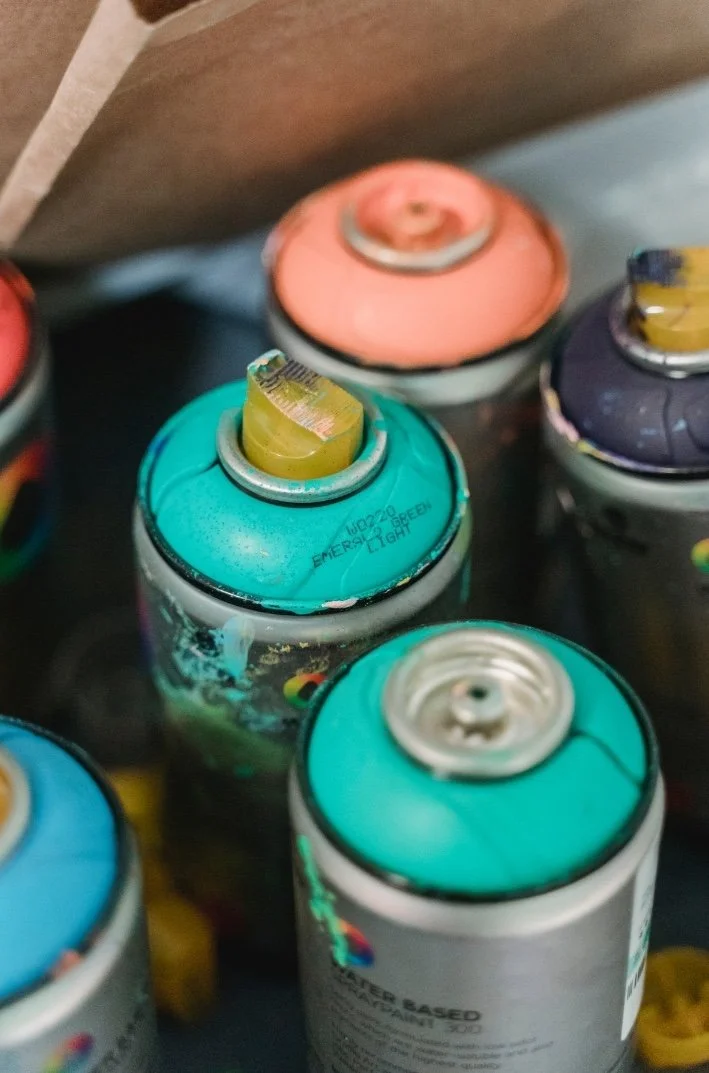 A close-up of colorful spray paint cans with the caps and nozzles visible.