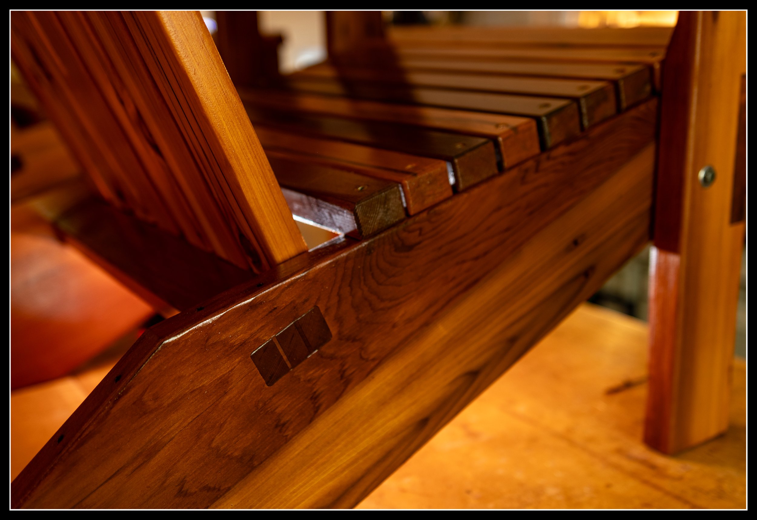 Detail of a cedar chair showing a wedged through tenon and a rich fiery long‑oil finish, highlighting traditional joinery and warm cedar grain.