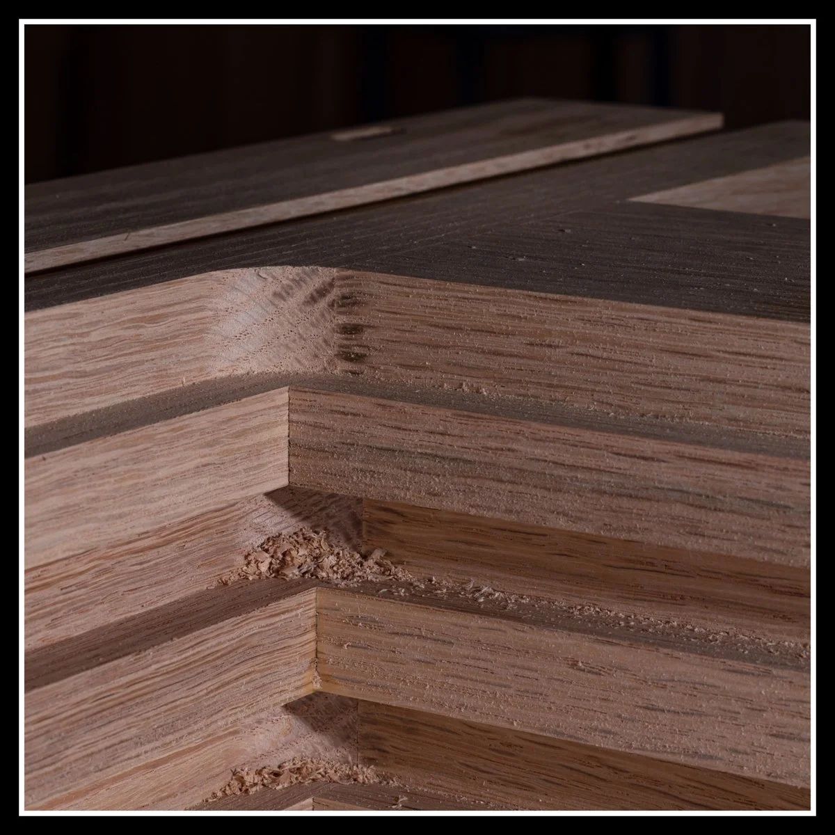 Freshly milled solid red oak frame components in a woodworking shop, showing crisp machining, visable open-pored grain structure, alternating growth layers, and clean stepped joinery cuts that highlights red oak's workability.