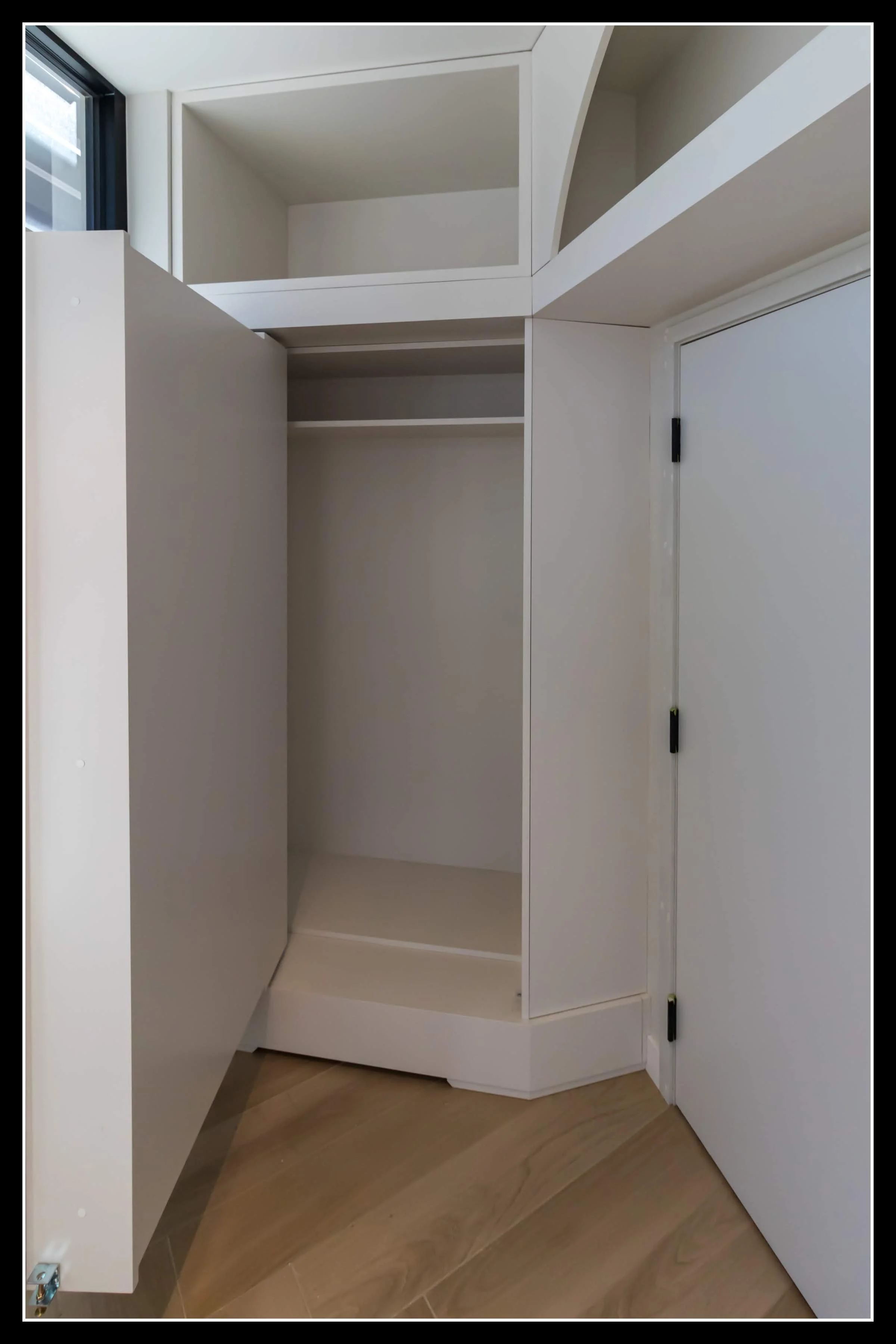 White built‑in cabinet with its concealed secret door open, showing hidden storage space behind the recessed panel design.