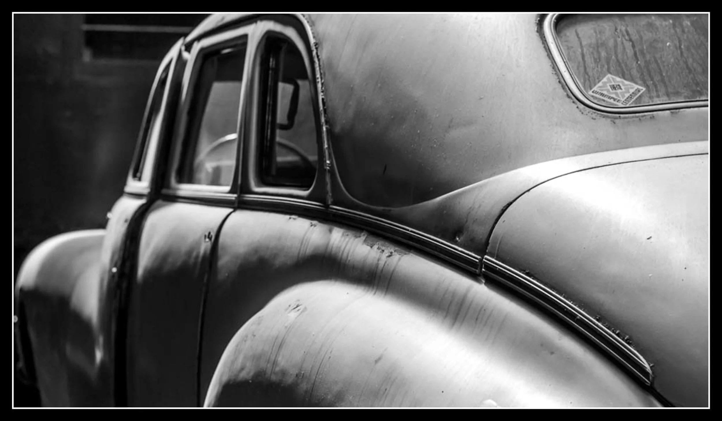 Black‑and‑white photo of an old railway‑museum car with worn metal, rounded body lines, and aged contours, showing the kind of details that teach careful, patient craftsmanship.