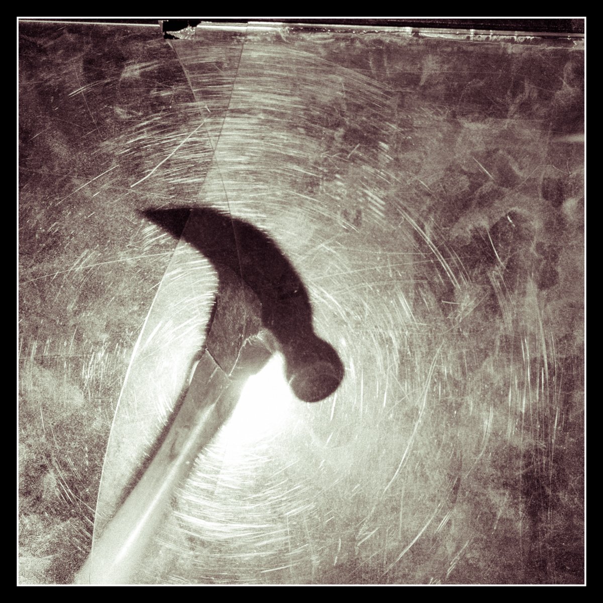 Hammer silhouette behind scratched plexi, lit with a back flash toward the lens and a second fill flash from below to reveal subtle texture.