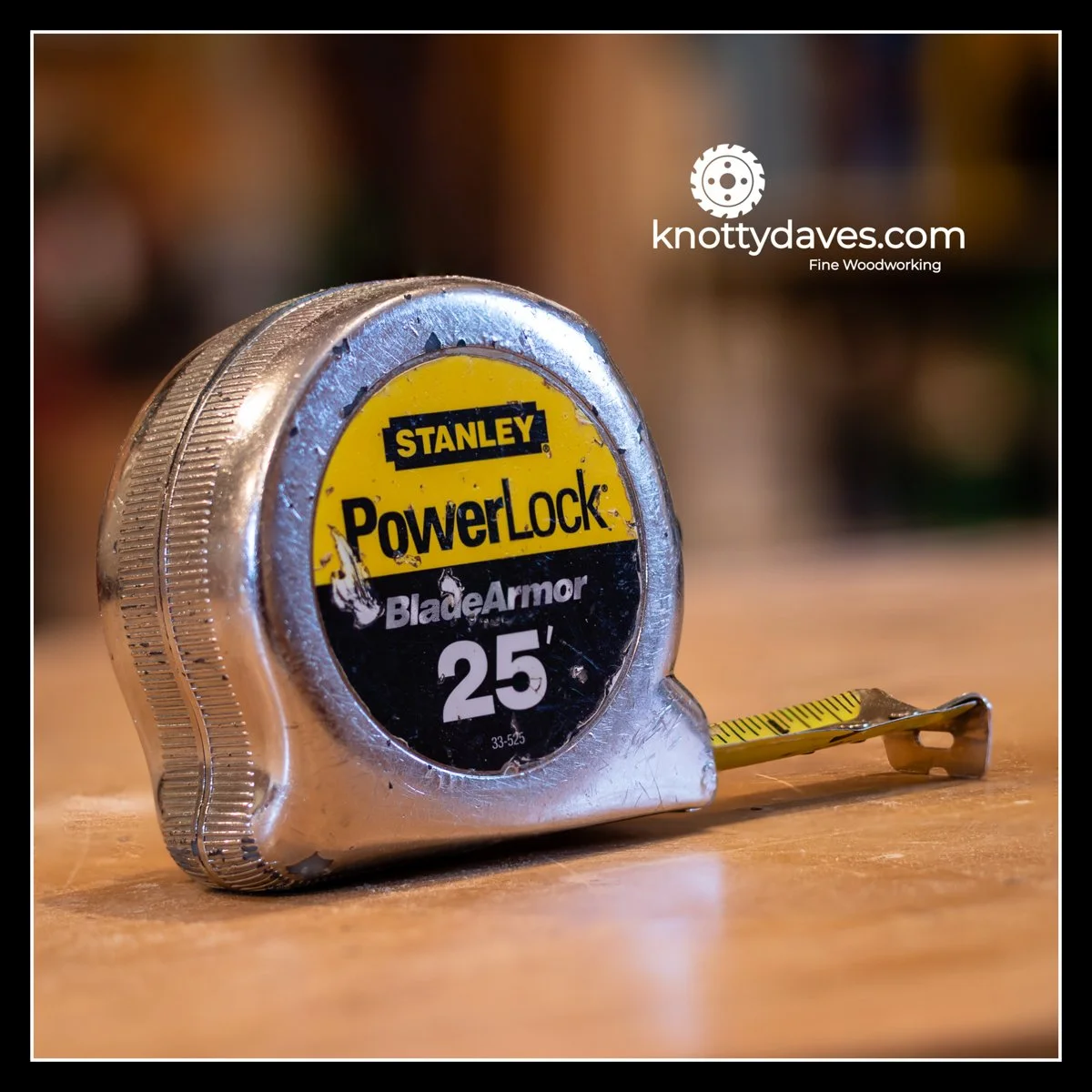 Stanley PowerLock 25' tape measure on a wooden surface with the blade slightly extended, showing metal case and yellow measuring tape.