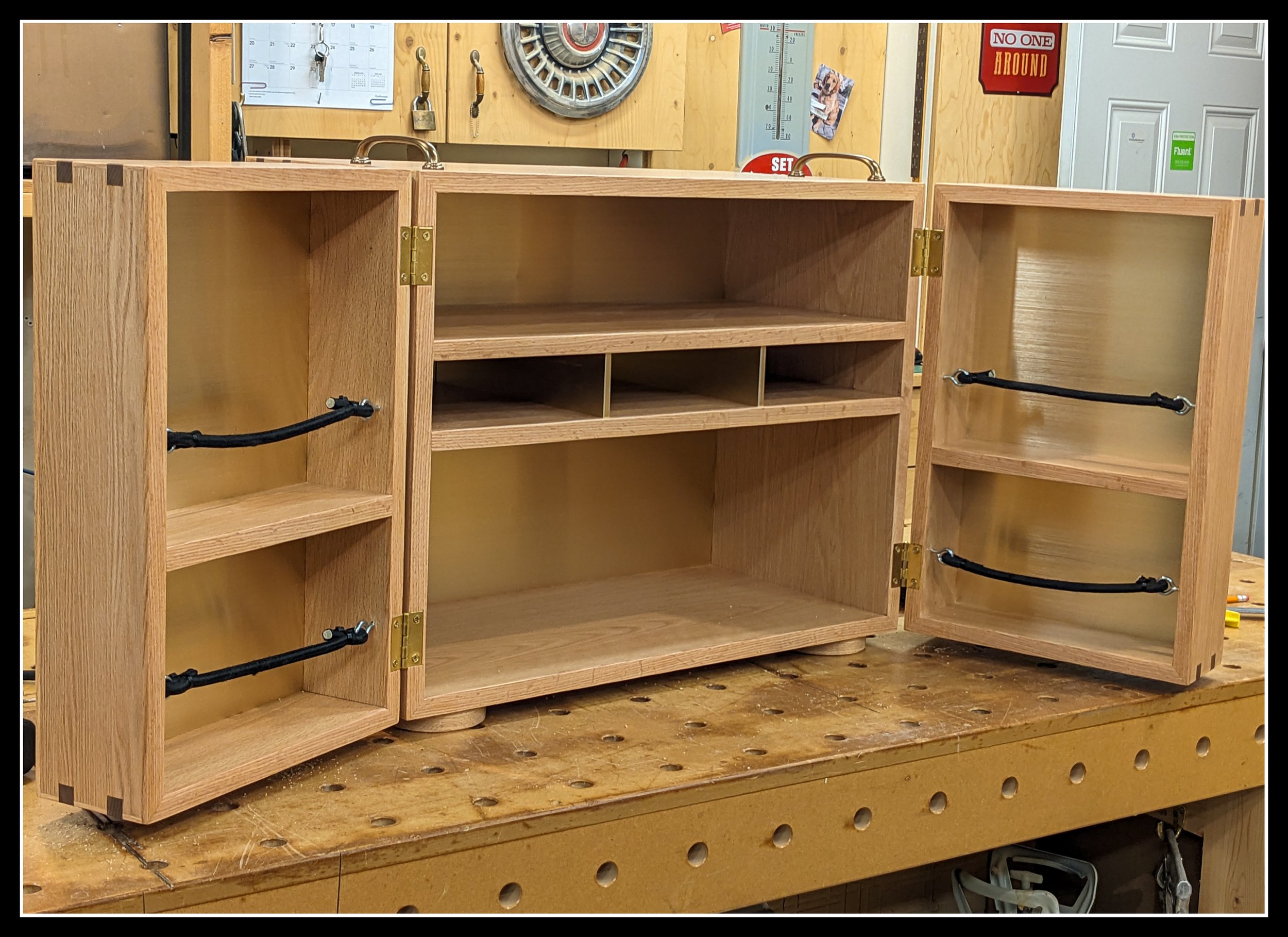 Hand‑built wooden Mini Kitchen cabinet with open doors showing shelves and compartments, designed for a Coleman stove and day‑trip cooking.
