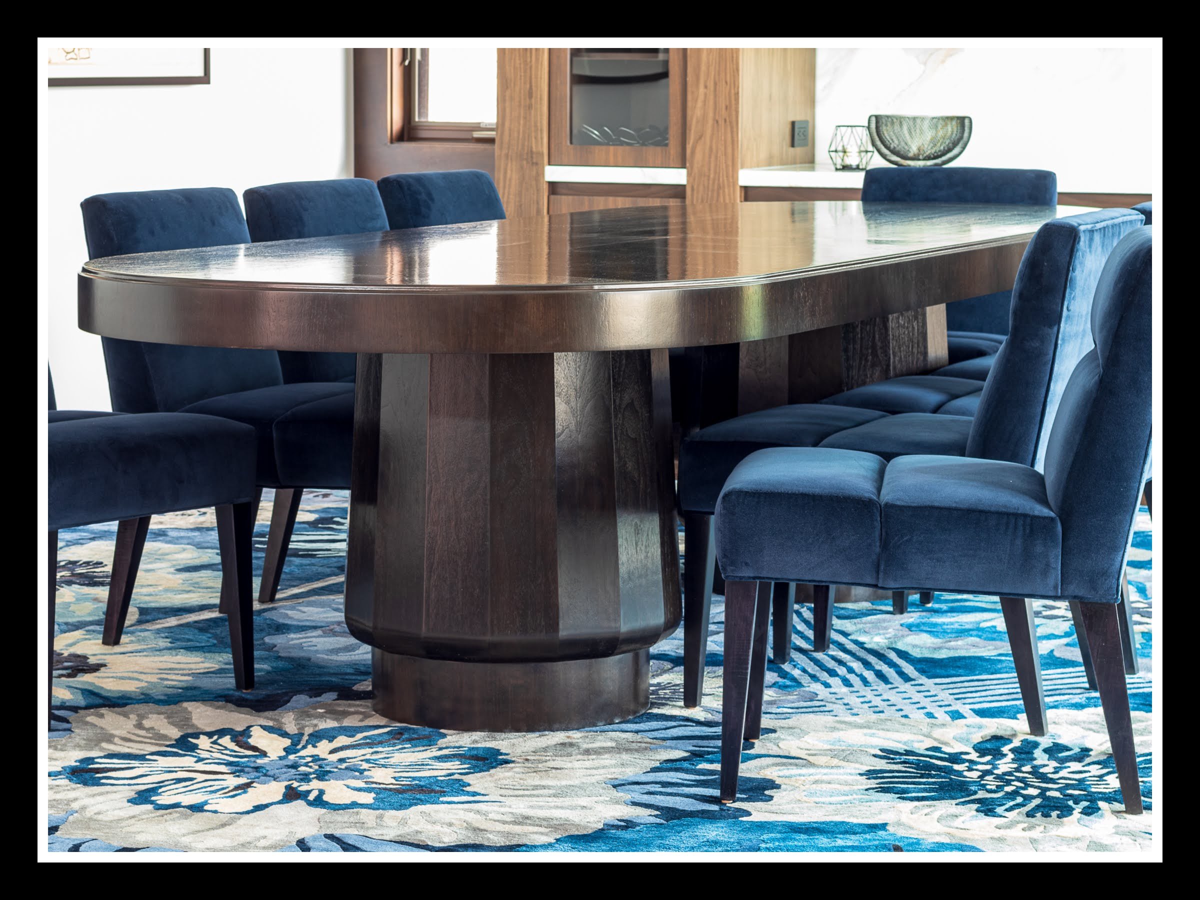 10‑foot walnut dining table with stained finish, dual conical pedestal bases, and 2K poly clear coat, shown in a modern dining room with upholstered chairs.