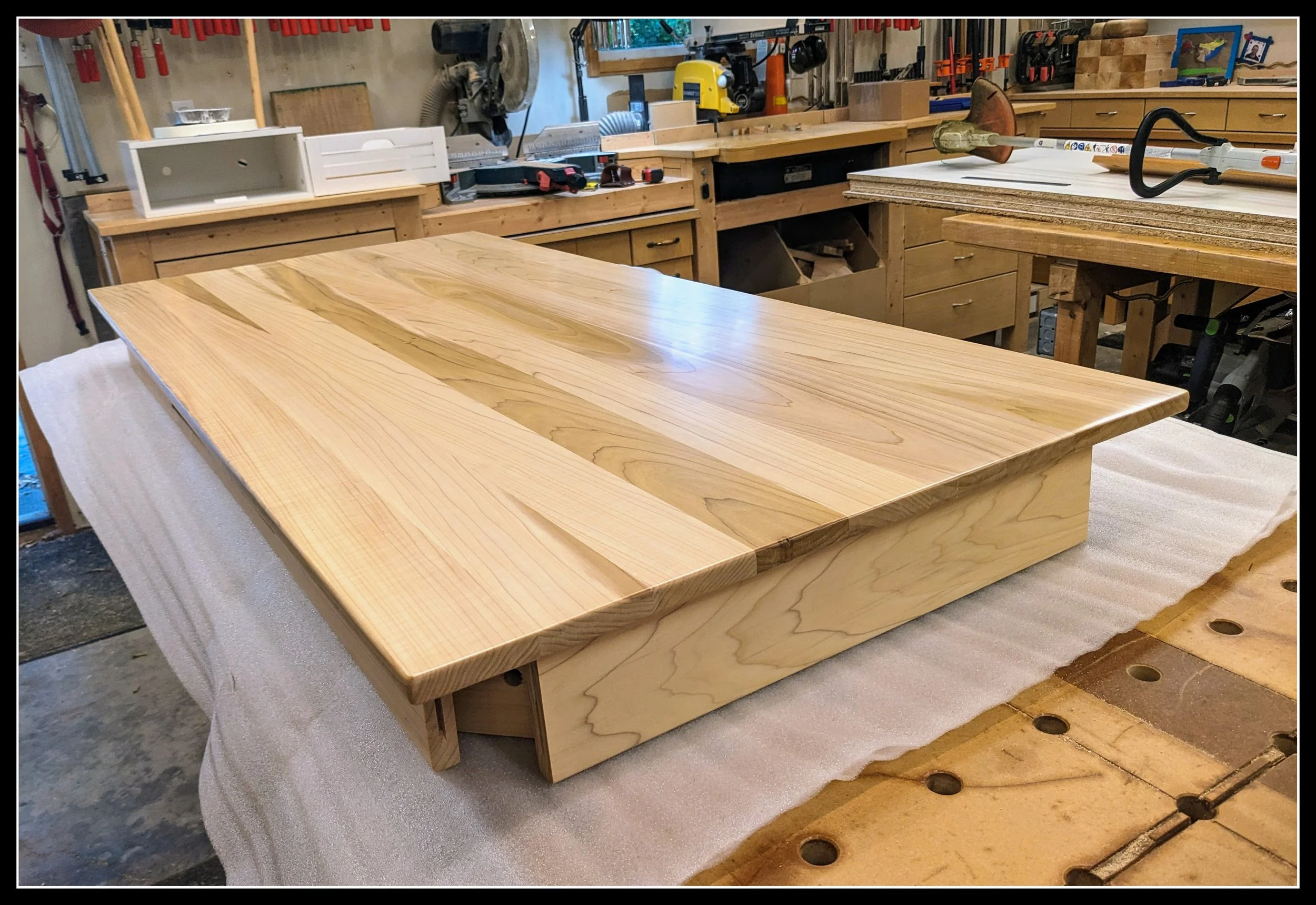 A poplar desk with a natural clear‑coat finish, showing the wood’s subtle green‑tan‑purple grain in a workshop setting.