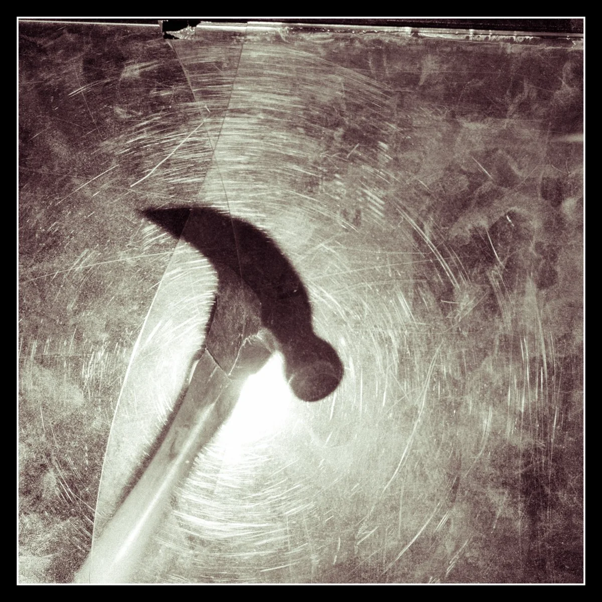 Hammer viewed through scratched and chipped plexiglass, symbolizing the rough, imperfect moments of shop life when the day isn’t going as planned.
