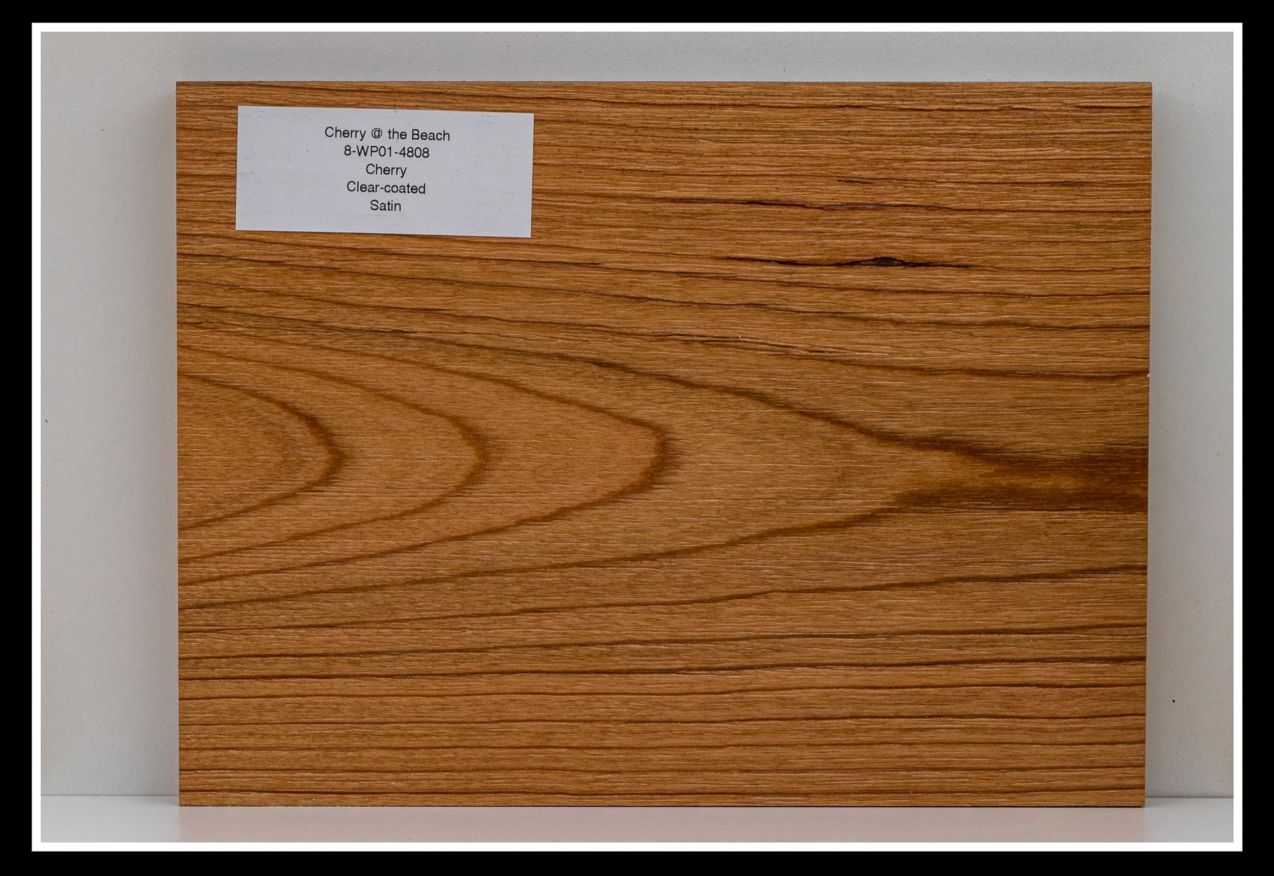 Close‑up of cherry wood grain with light scraping, warm stain, brushed texture, and a satin 2K poly finish.