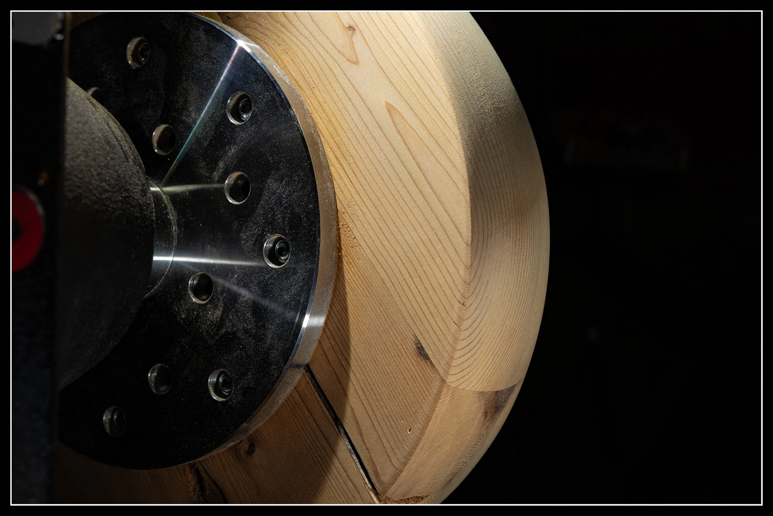 Cedar sphere on the lathe, freshly sanded and showing smooth grain and clean turning work.