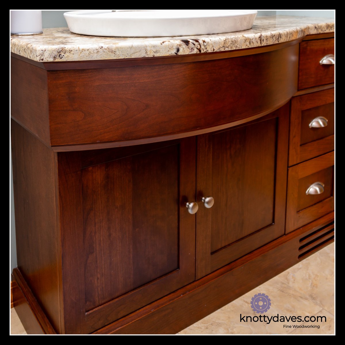 Cherry vanity with curved front, base vent, and warm stained finish.