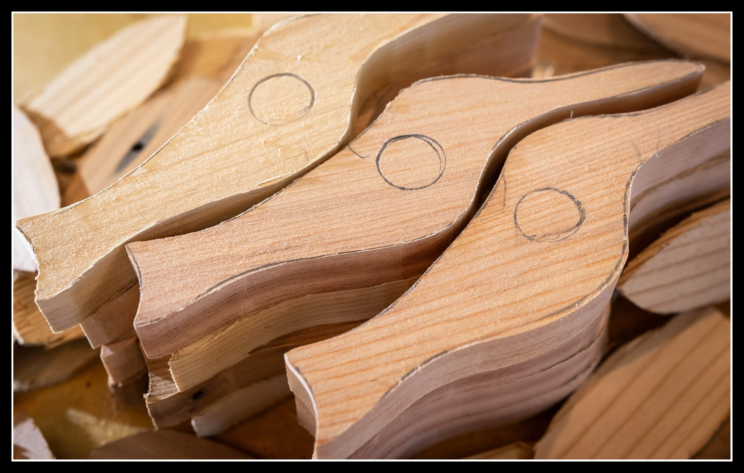 Stacks of curved wooden pieces with pencil markings.