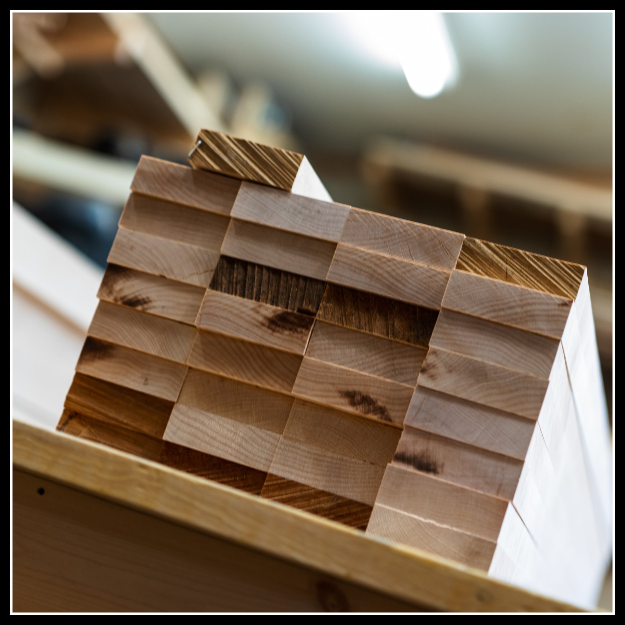 Stack of maple boards freshly milled, showing end grain cuts with light burning from machining.