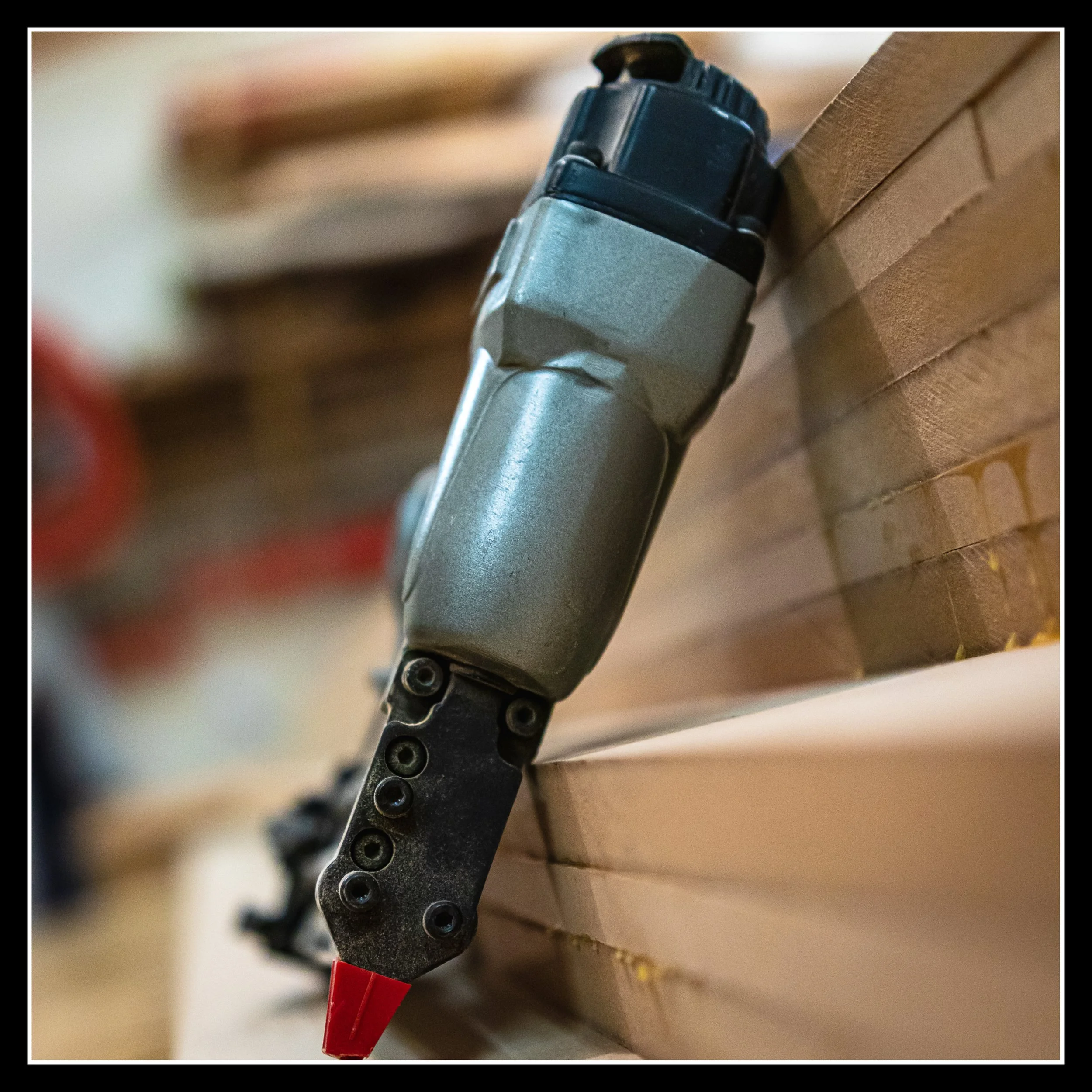 ROK 23‑gauge pin nailer leaning against a stack of wood on the workbench.