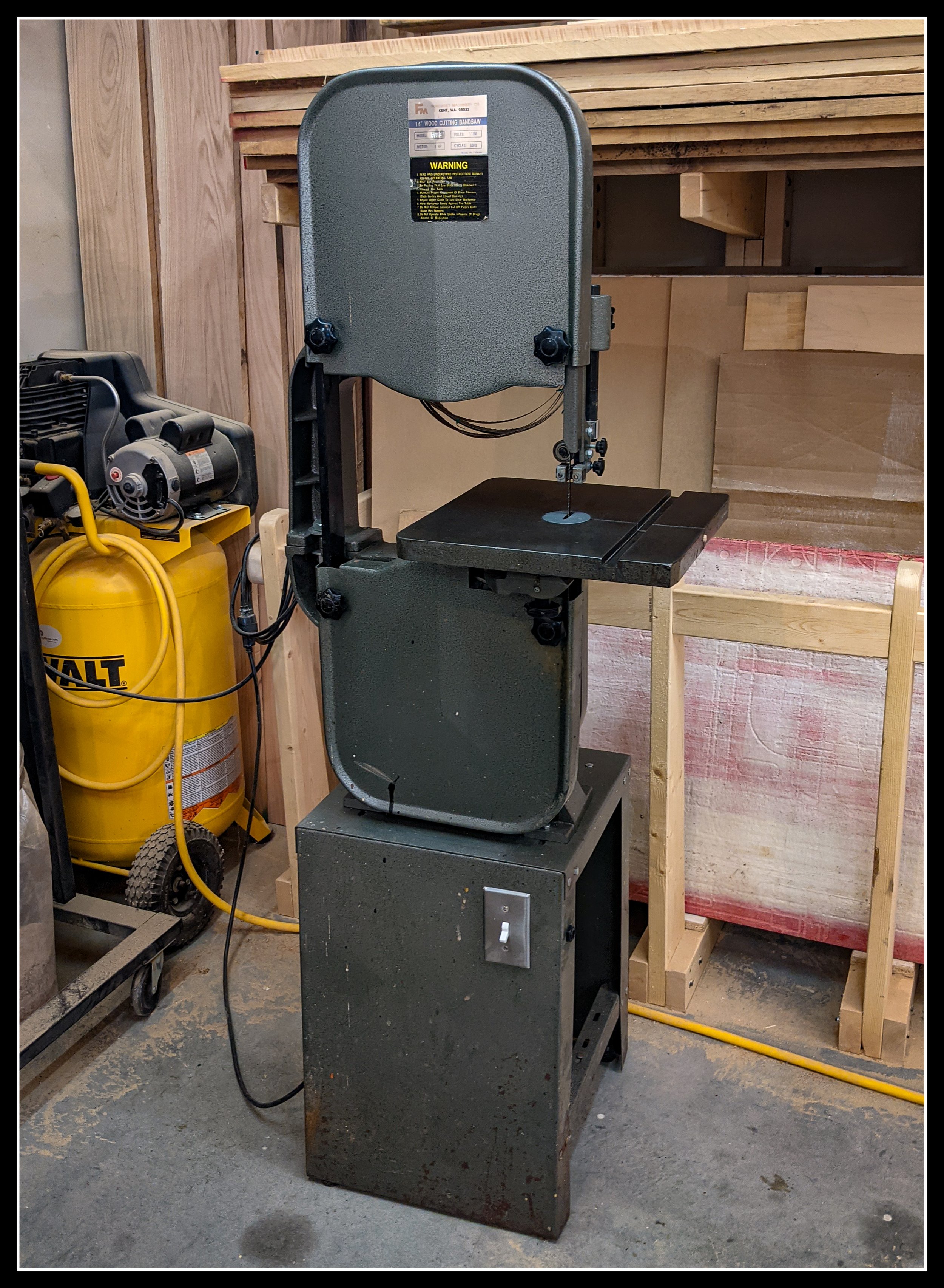 Foremost 14-inch bandsaw from the 1980s with cast-iron frame and induction motor, shown in a woodworking shop beside a DeWalt air compressor.