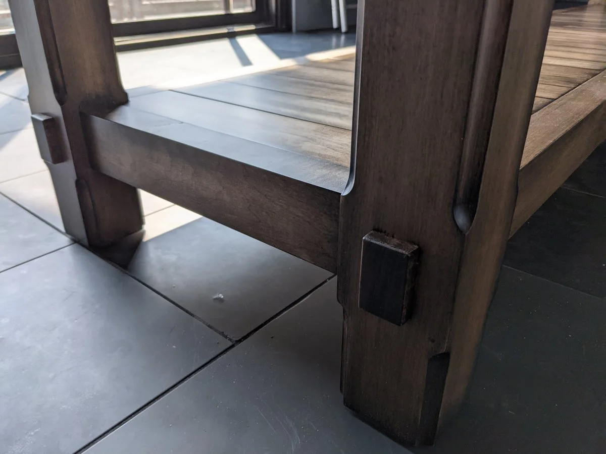 Maple table leg with exposed through‑tenon joinery and pegged construction, showing clean finish and sturdy woodworking detail.