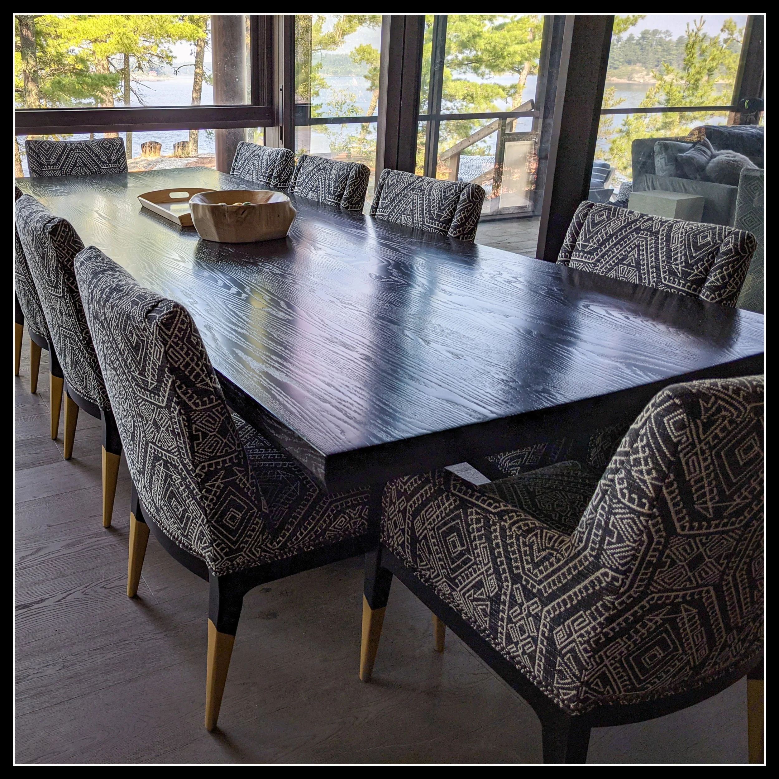 12‑foot dark‑stained red oak dining table in modern dining room with patterned chairs and hardwood grain detail.