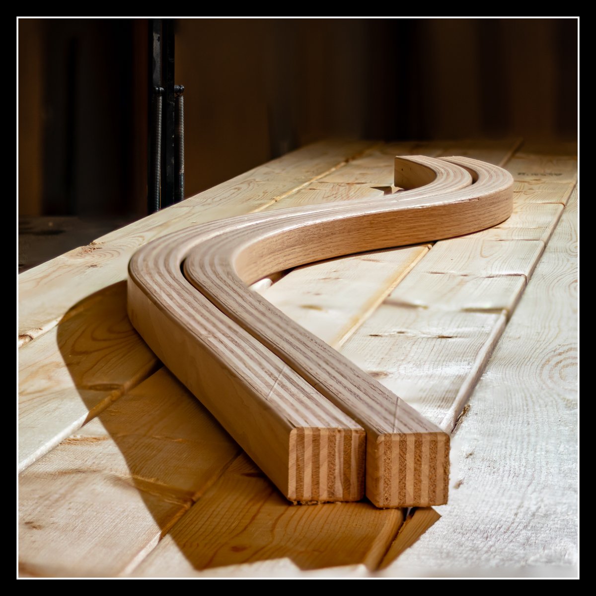 Bent lamination of red oak and maple resting on spruce in the shop, a long‑used technique from my early woodworking years.