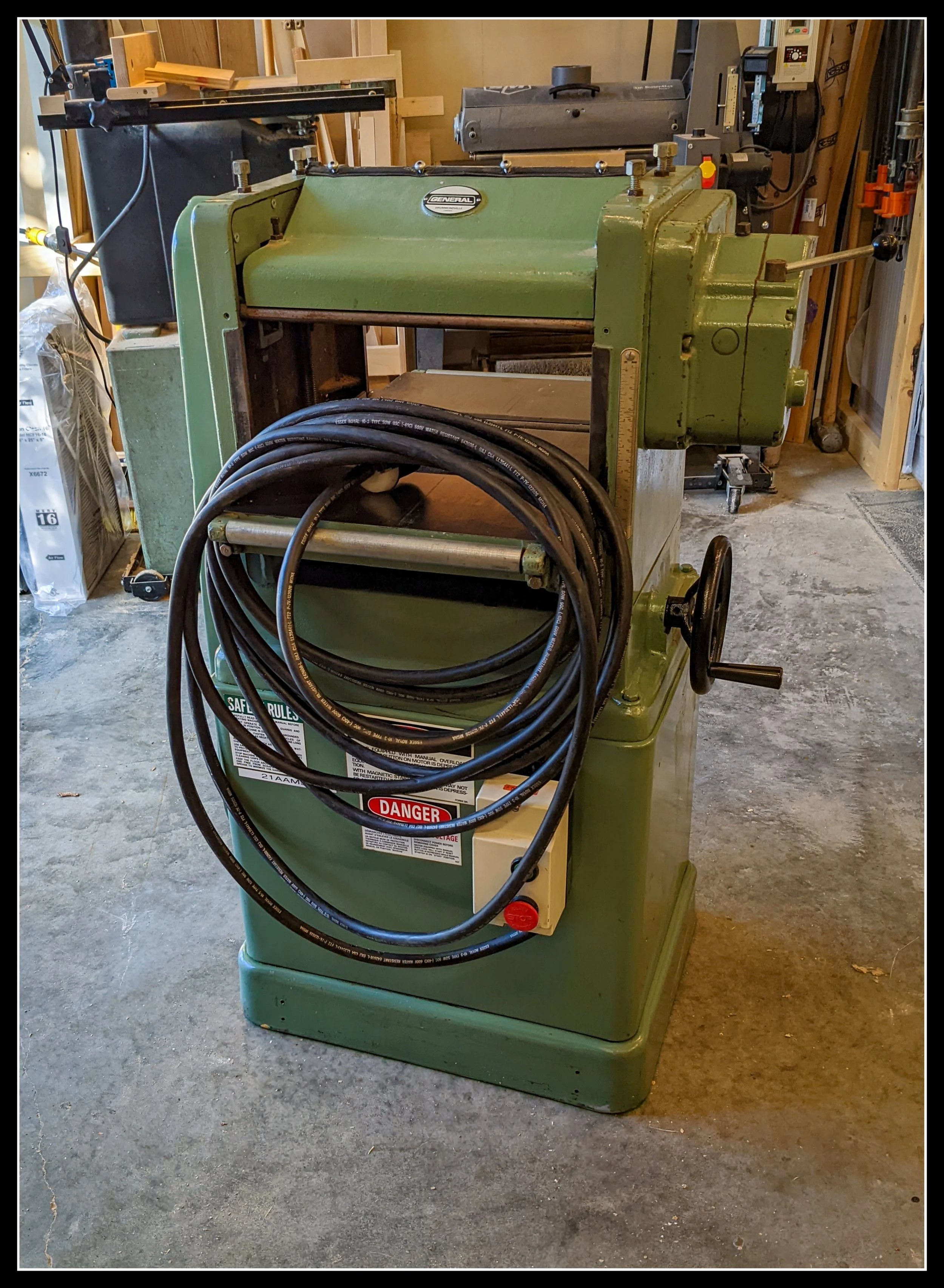 General 130 thickness planer freshly unwrapped in the workshop, showing cast‑iron body, crank handle, and first setup before use.