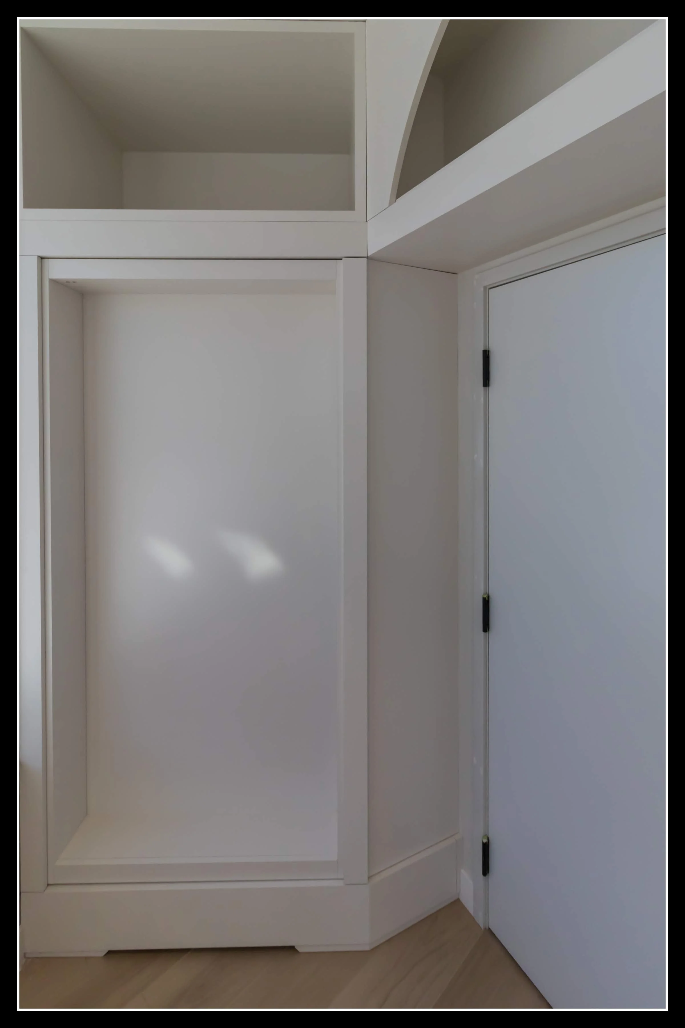 White built‑in cabinet with recessed panels and a concealed secret door integrated into the design.