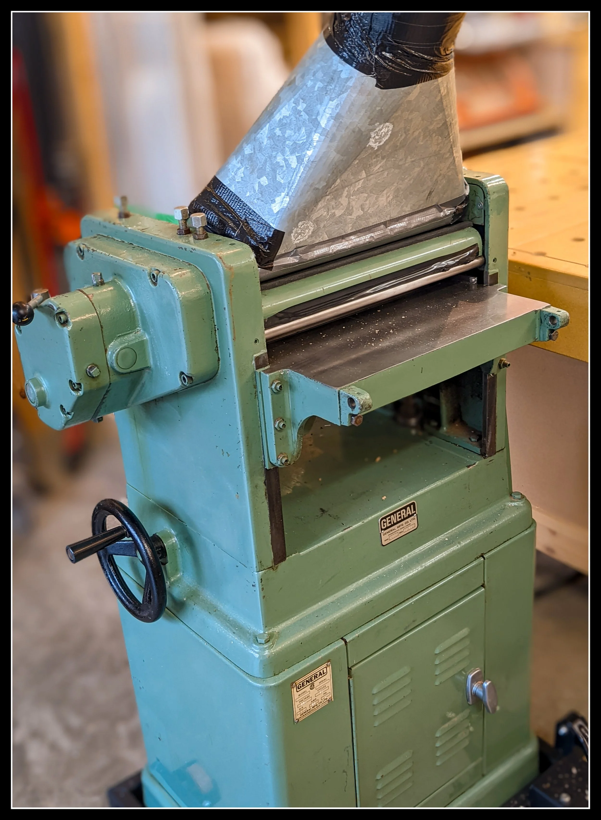 General 130 thickness planer set up in the workshop, tuned and ready for use, shown with the outfeed roller temporarily removed for repair.