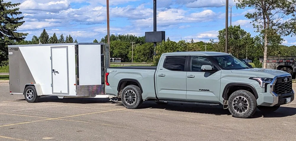 A Toyota Tundra pickup truck attached to a white enclosed trailer parked in a parking lot.