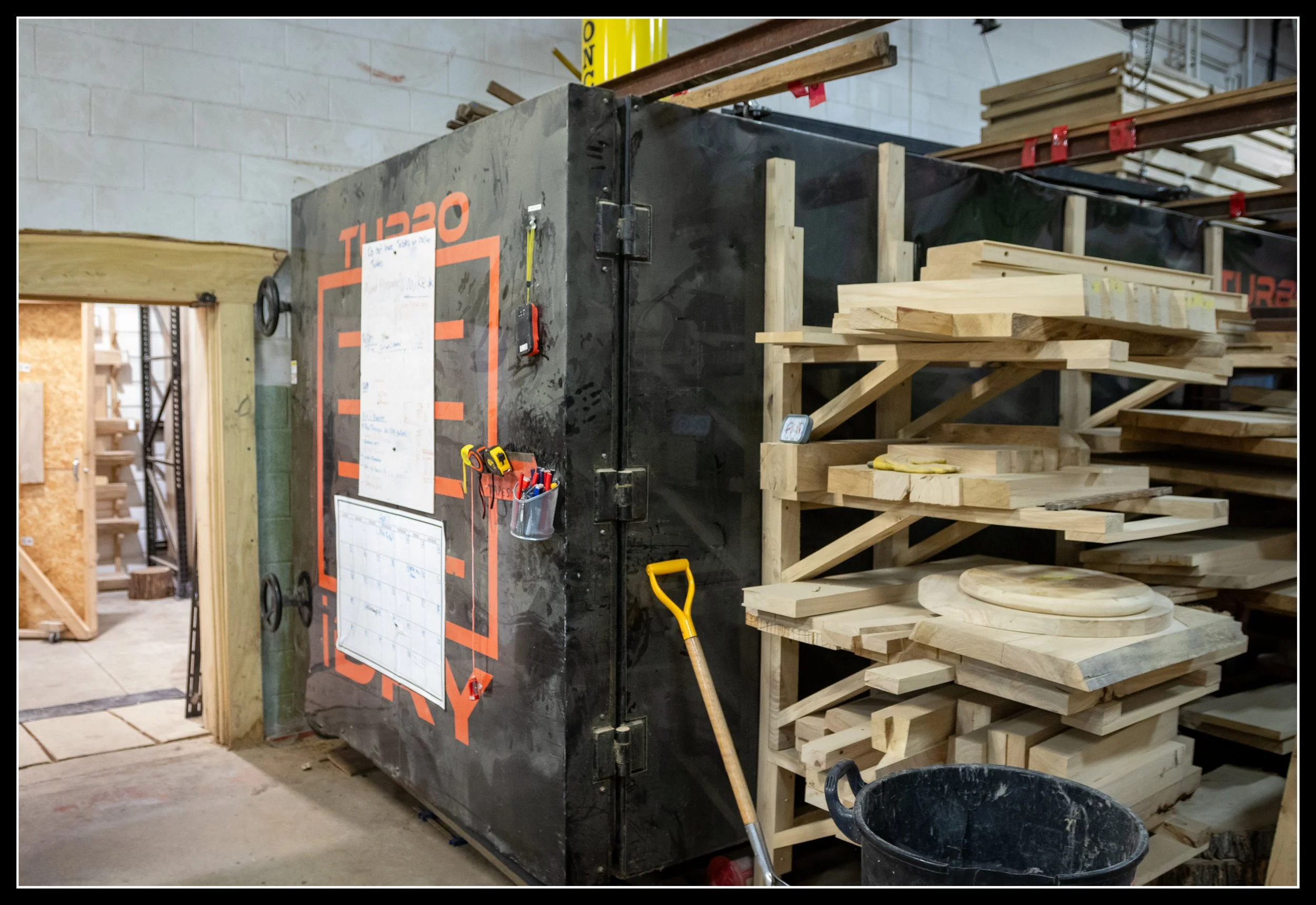 Plate kiln with overhead bladder used to dry elm, applying heated pressure to prevent warping and increase yield.