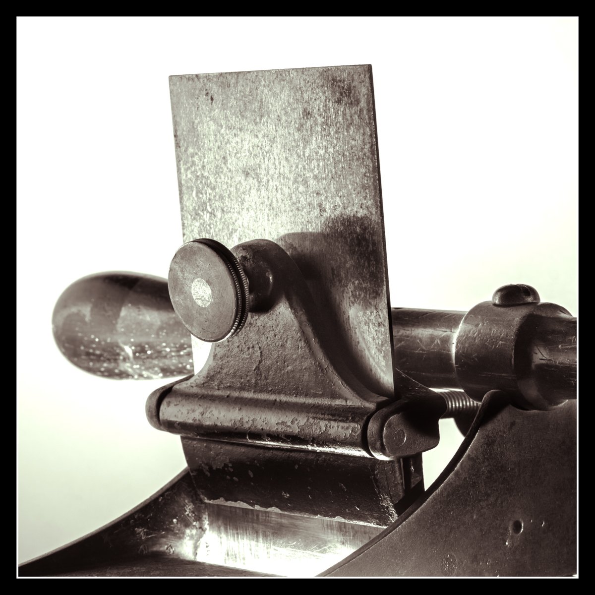 Old scraper plane lit with a side flash and a second flash through the mouth to highlight the blade and metal texture.